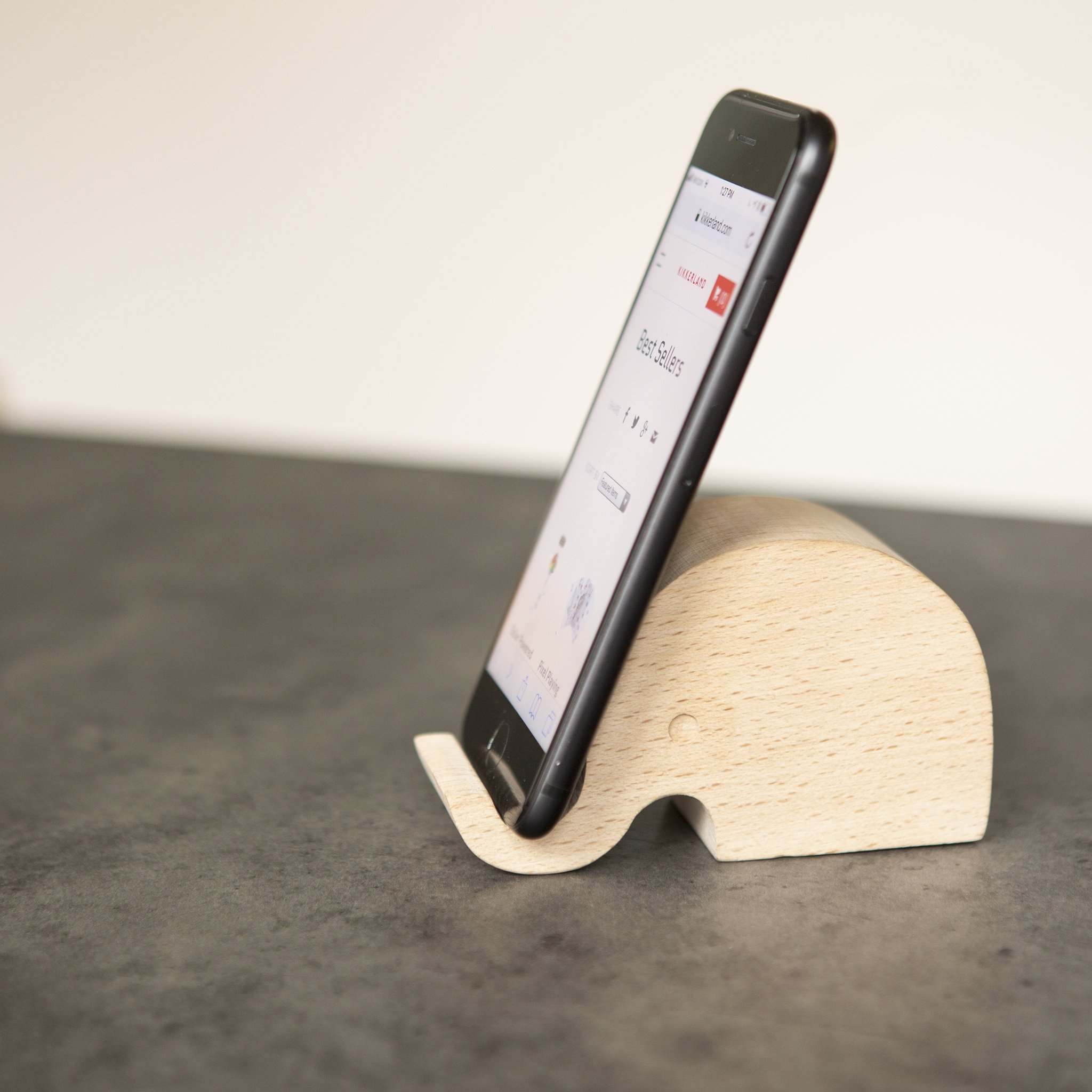 Smartphone steht im Elefanten-Handyhalter aus Buchenholz auf dem Tisch