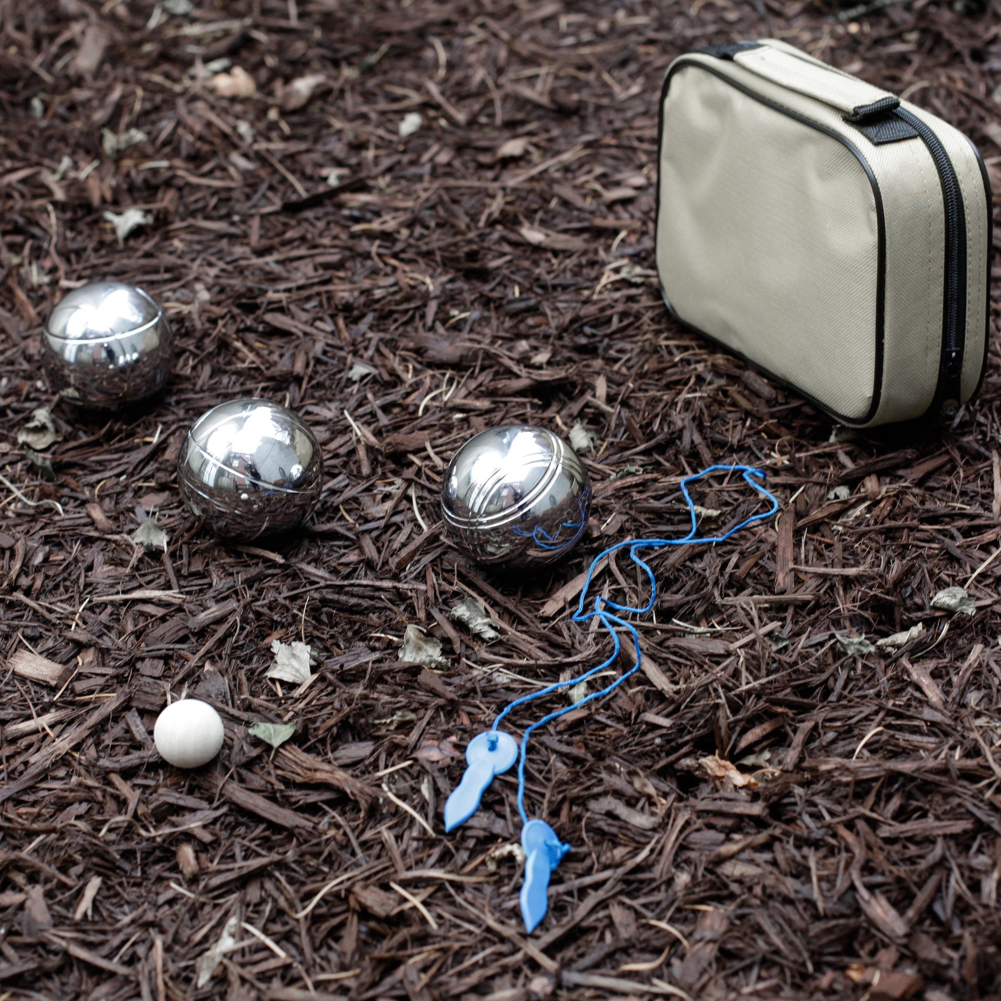 Jeu de boules avec boules en métal, cochonnet et sac de transport clair sur du paillis