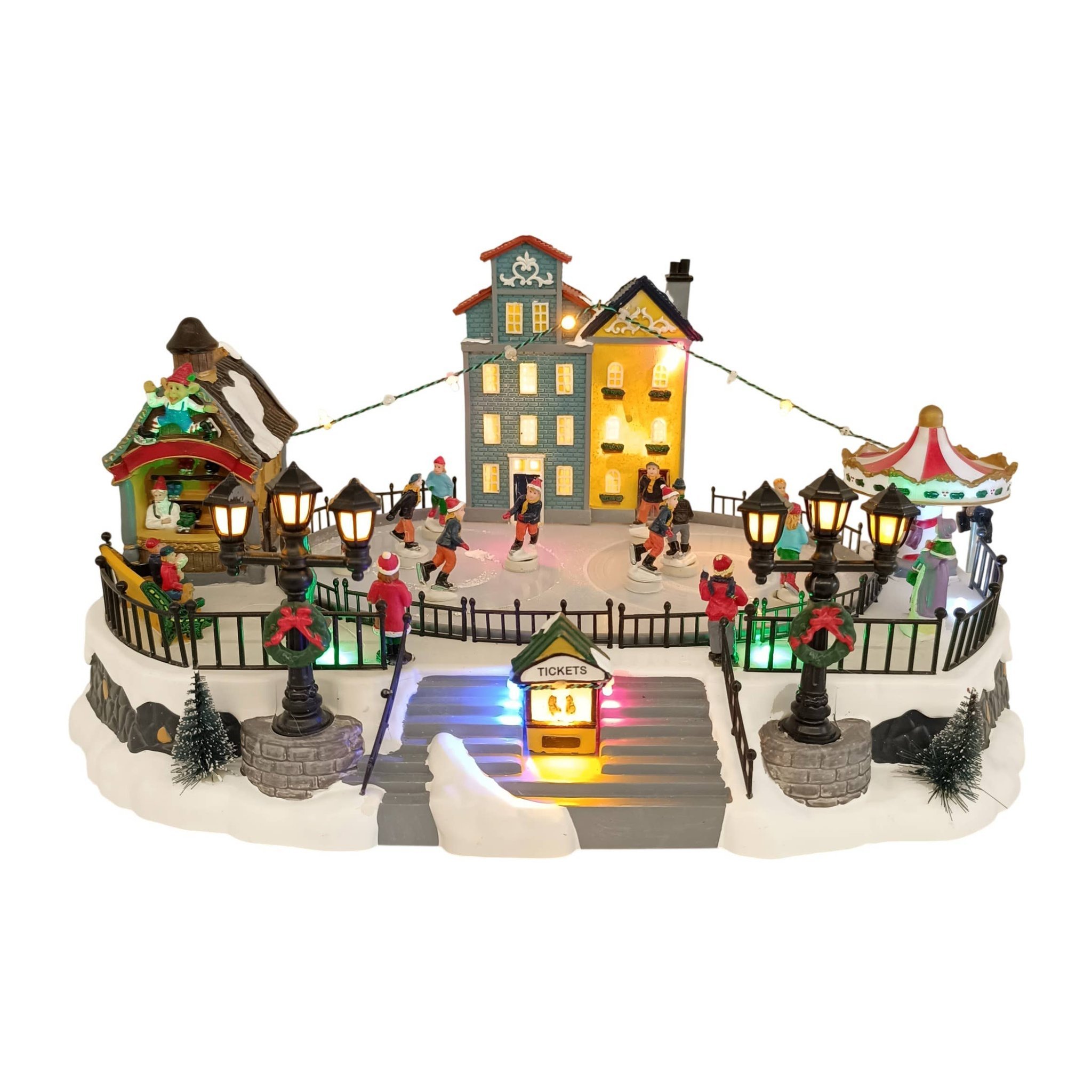 Illuminated Christmas village with ice rink, skaters, houses and carousel