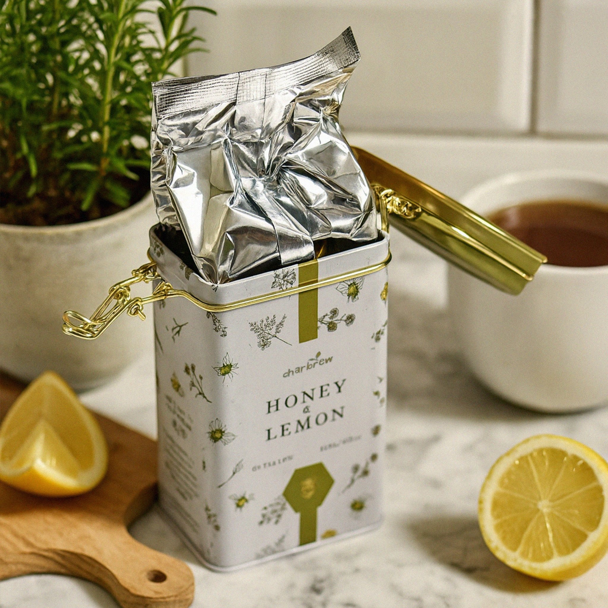 Latta di tè aperta con chiusura a leva e sacchetto in alluminio, in cucina accanto a un limone