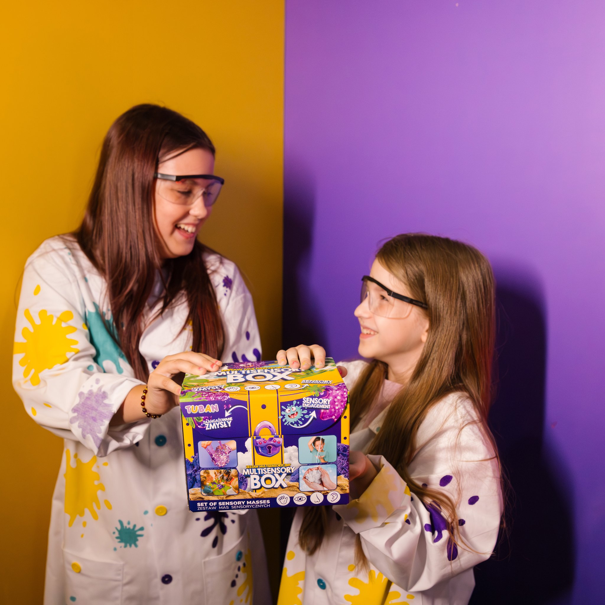 Ragazza con occhiali protettivi felice della scatola multisensoriale con slime, sabbia e neve artificiale