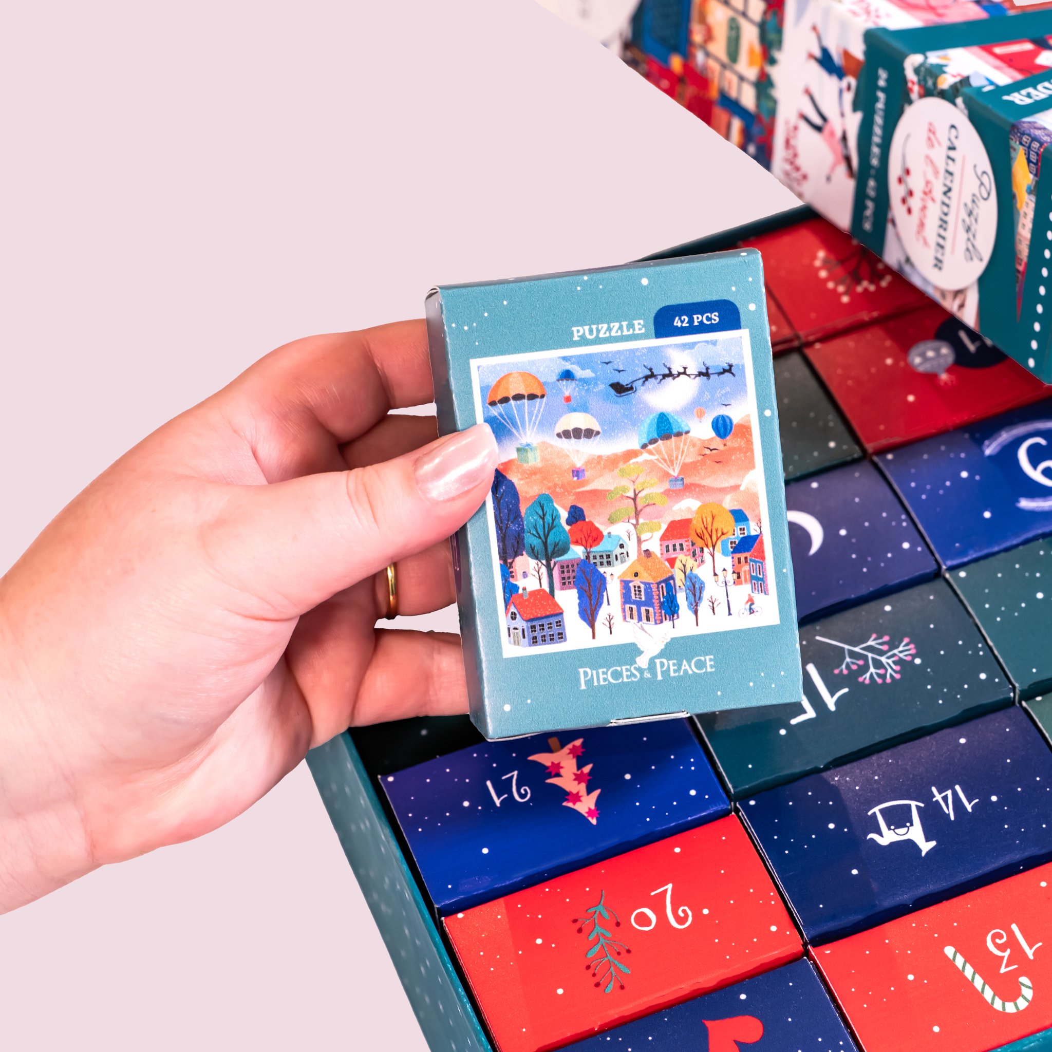 Main prenant un mini-puzzle dans les petites boîtes numérotées du calendrier de l'Avent
