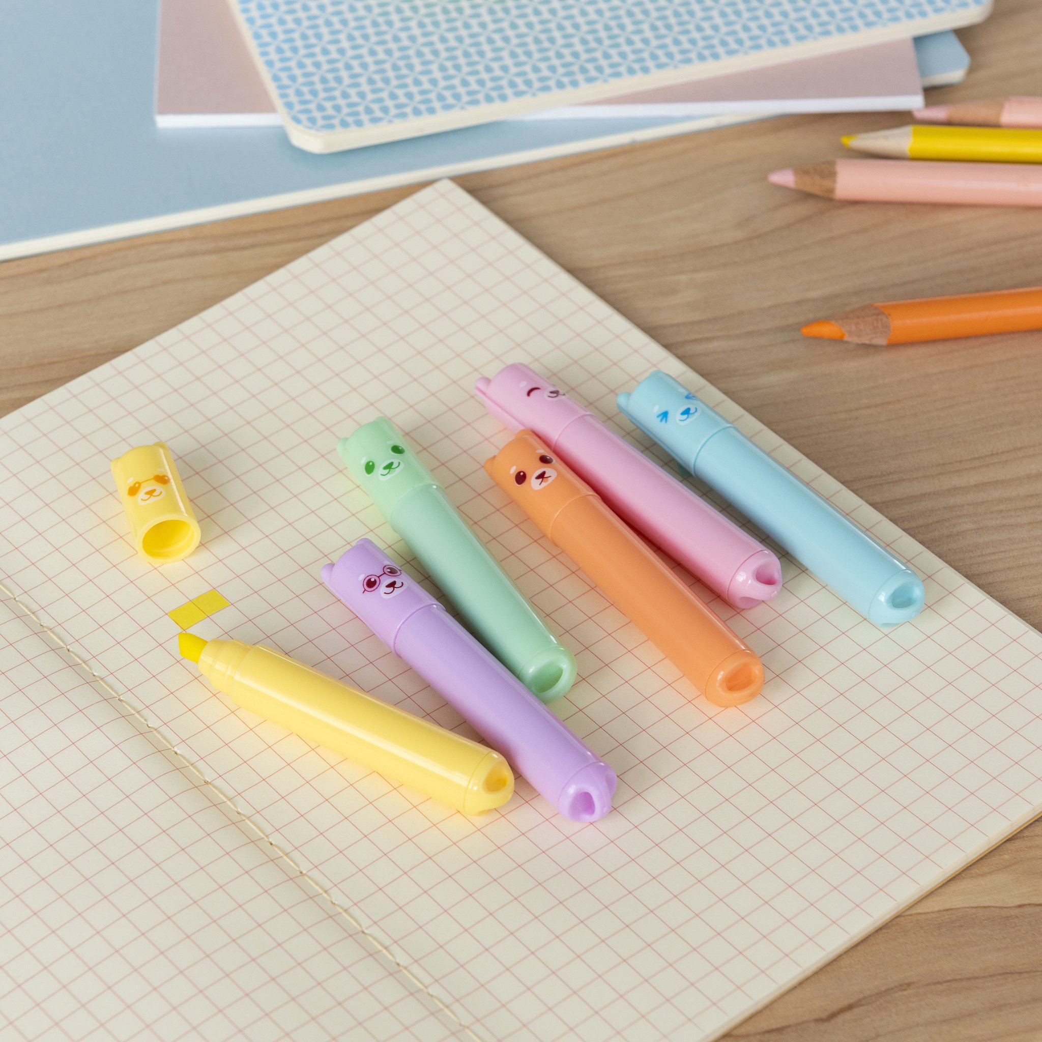 Mini evidenziatori orsetto in colori pastello su un quaderno con matite