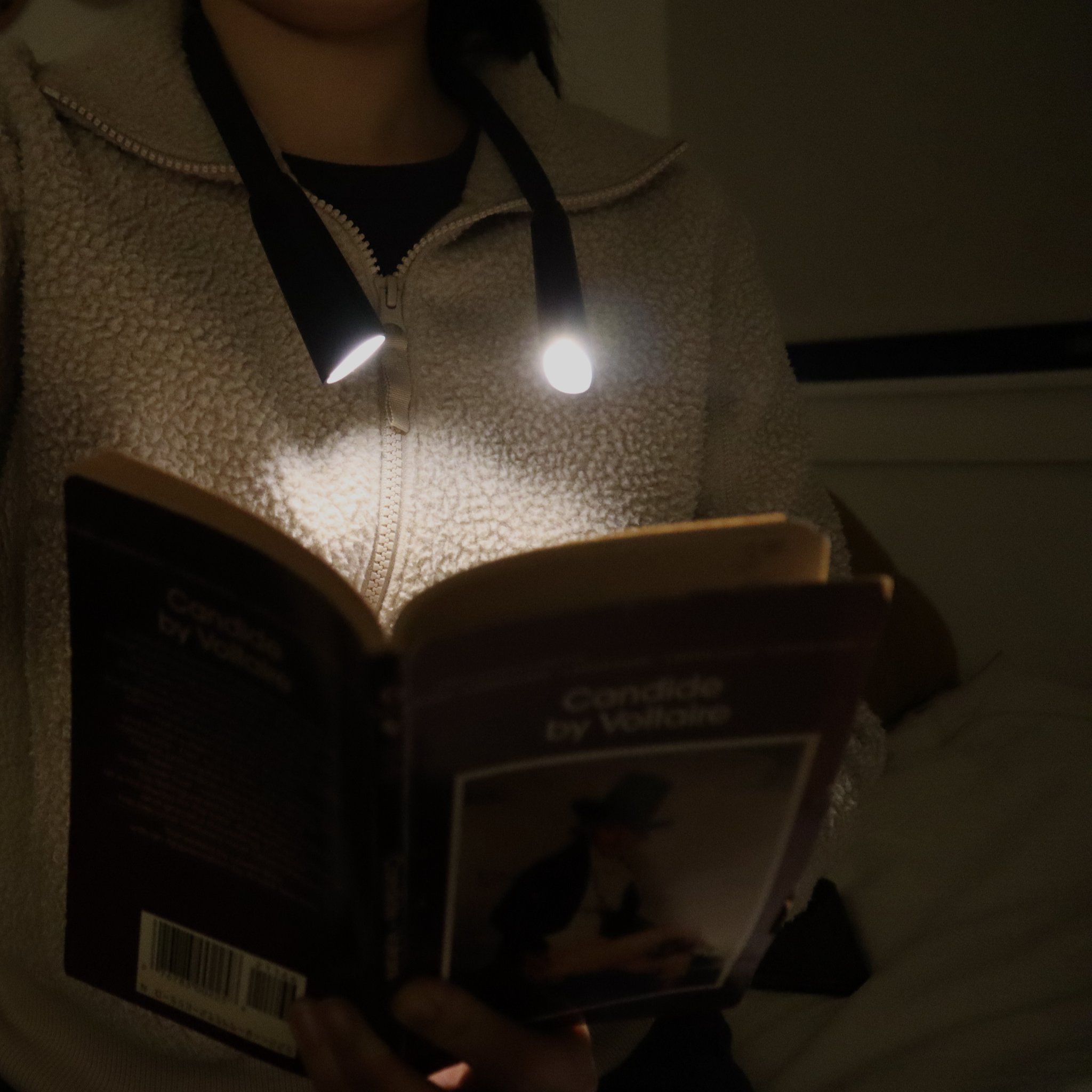 Reading light around the neck, both LED heads pointed at the book