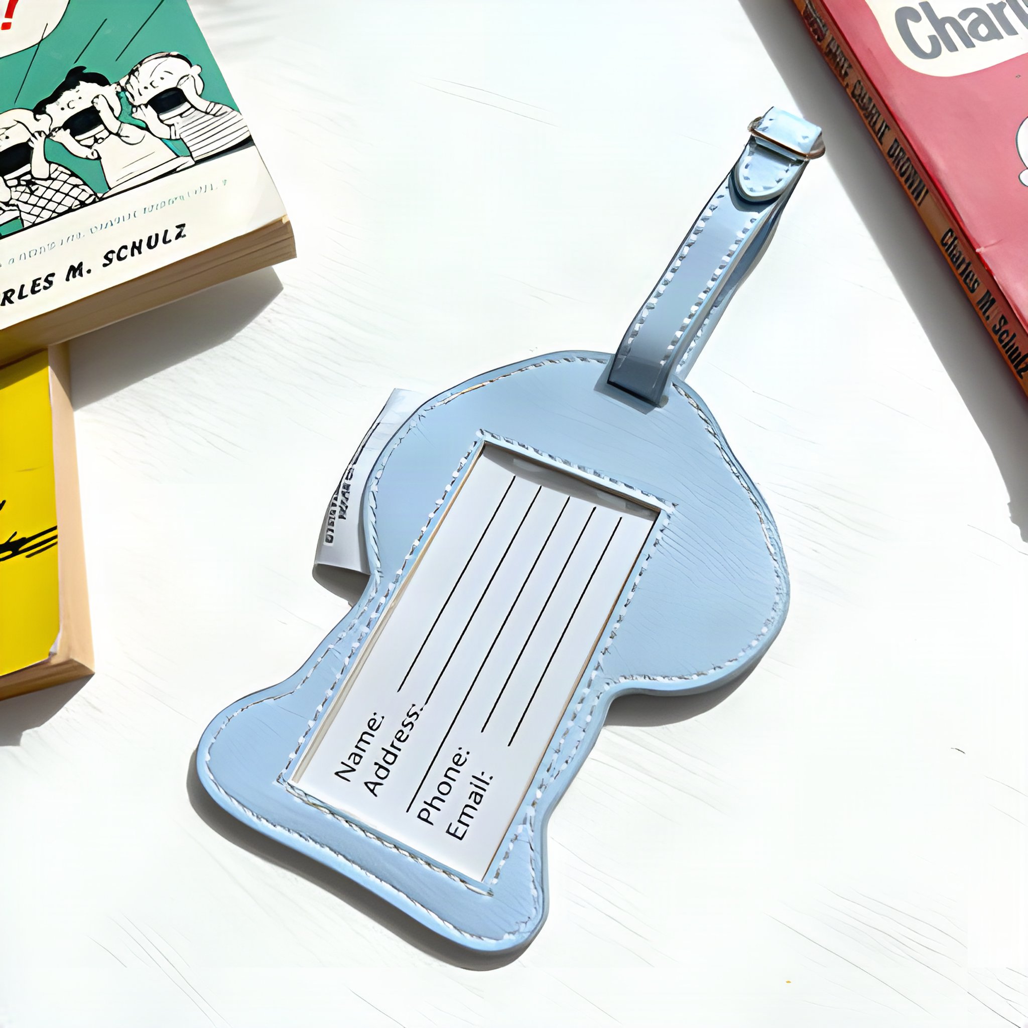 Back of the luggage tag with address card, on Peanuts books