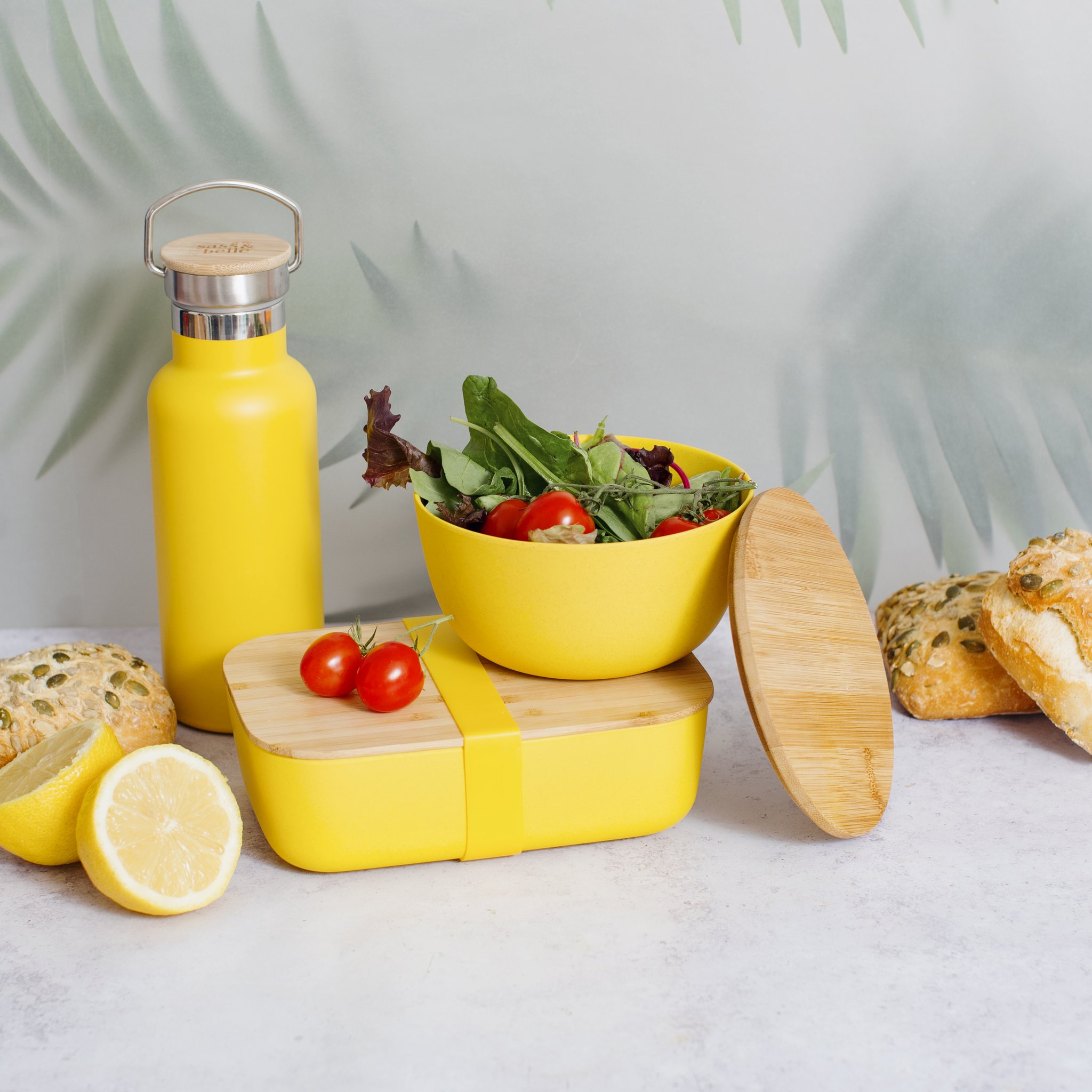 Senfgelbe Wasserflasche mit gelber Lunchbox, Salat und Zitrone