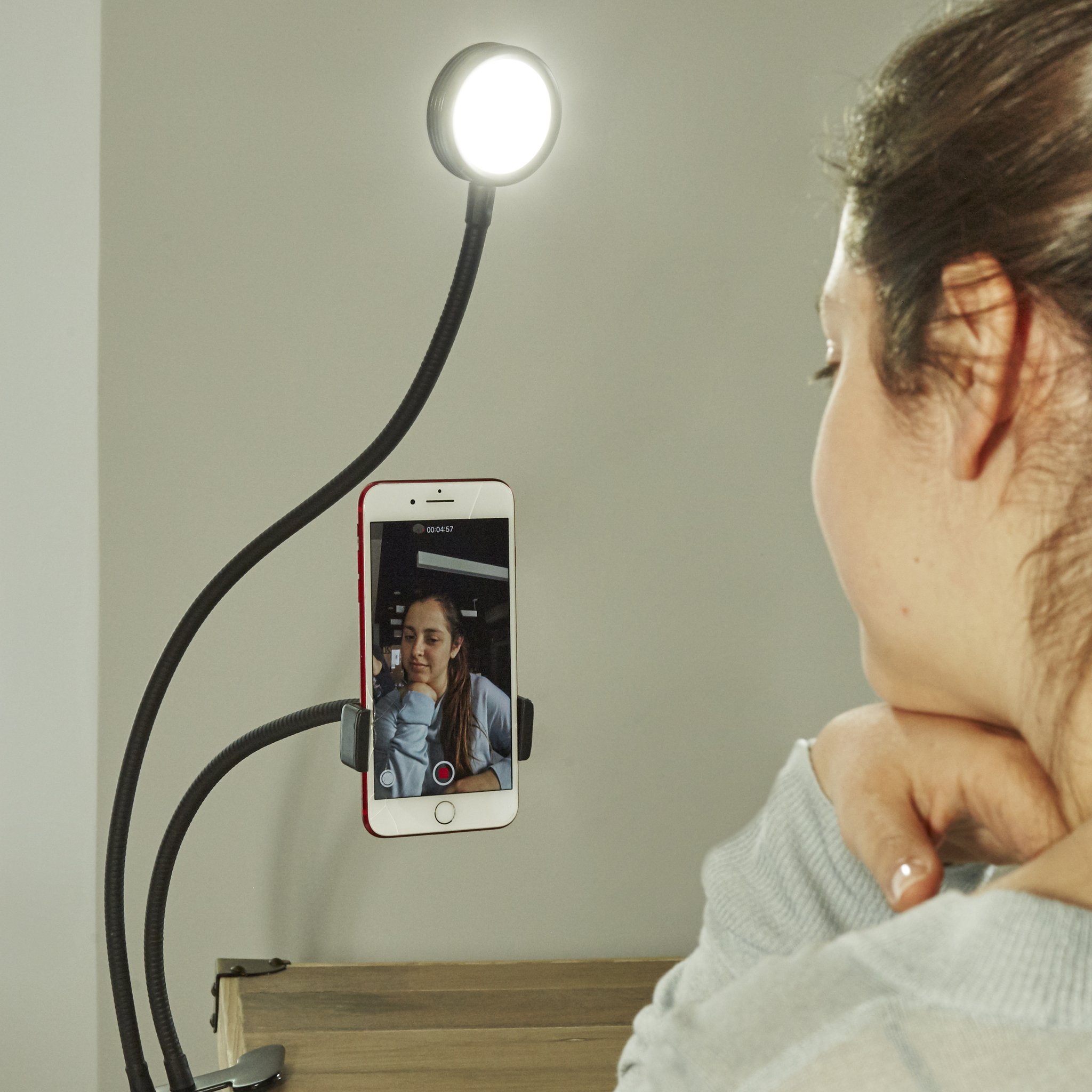 Live streaming kit with ring light and phone holder on the table, woman from behind