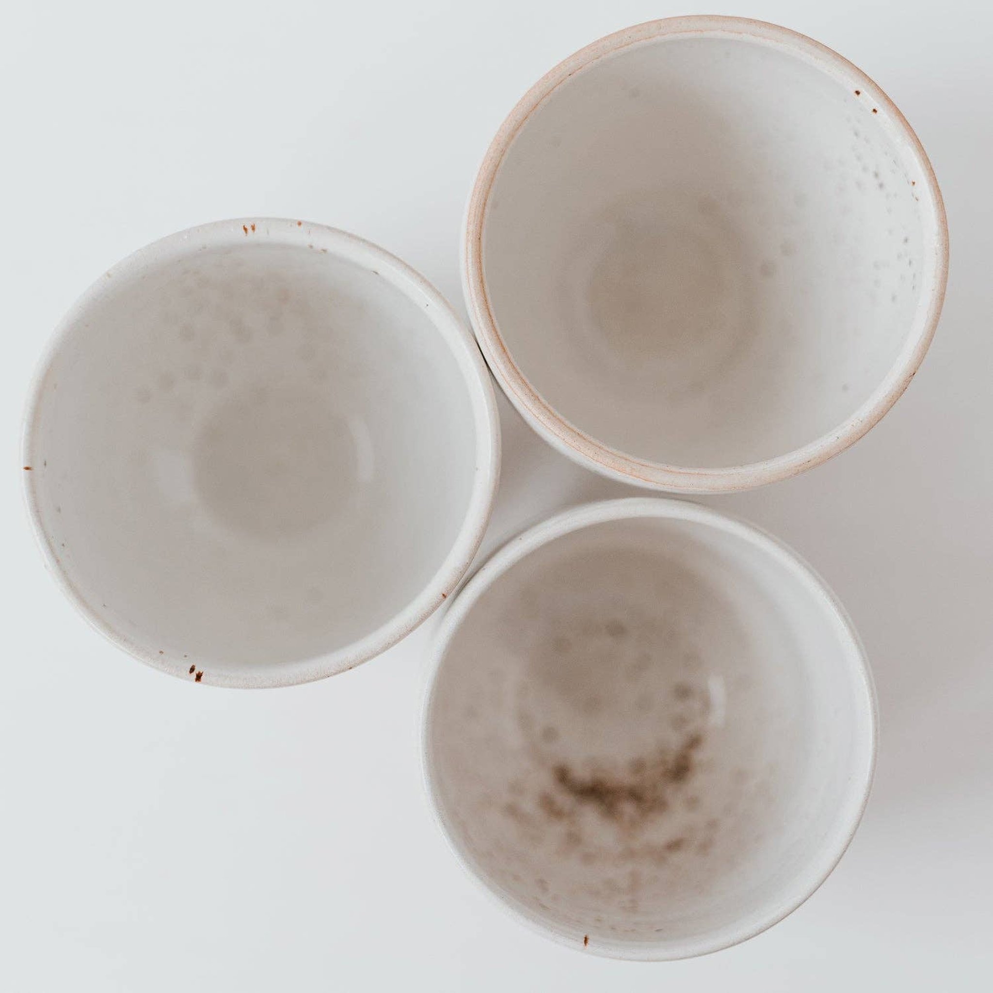 Drei handgemachte Steingut-Becher von oben, jeder mit eigener Glasur und Sprenkelung