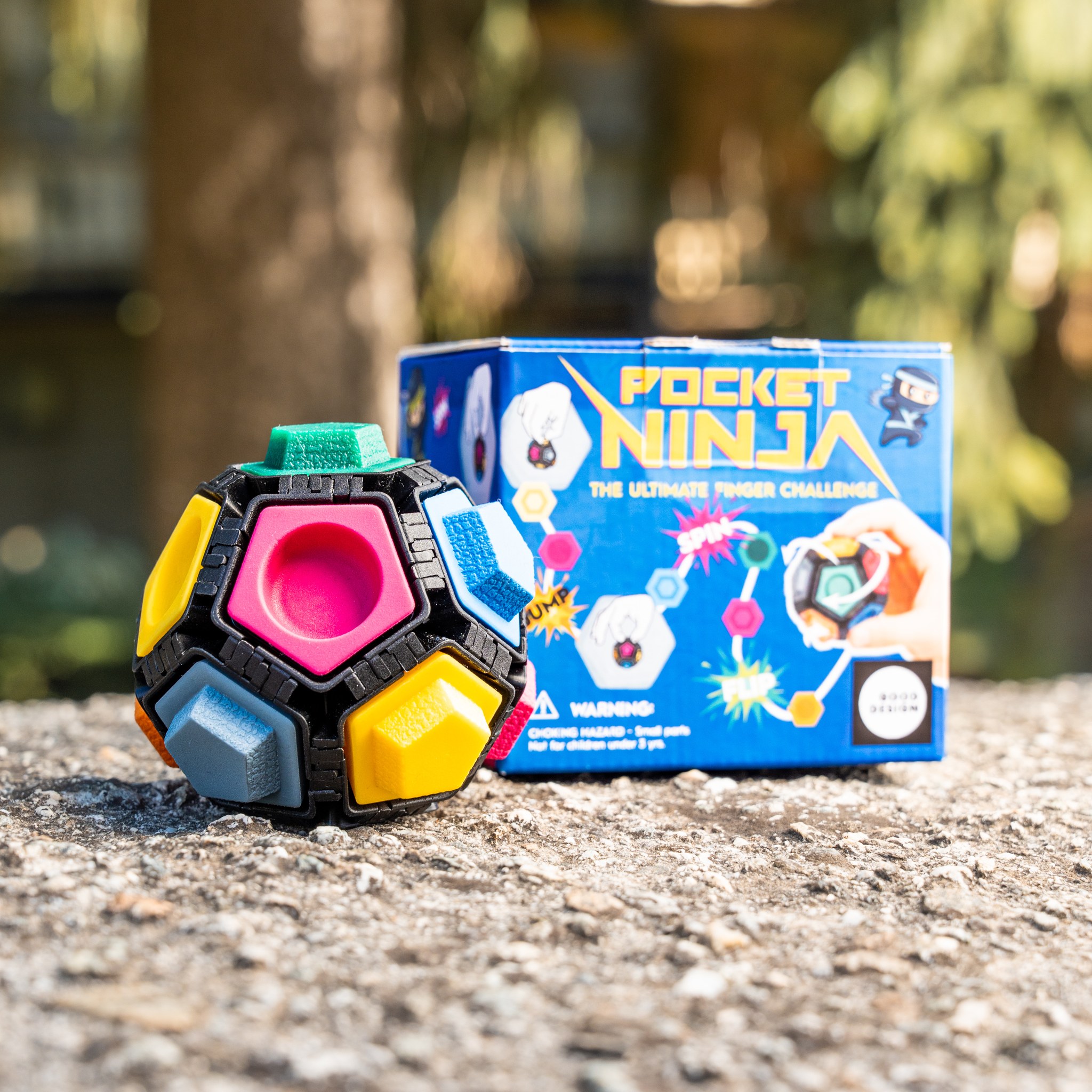 Pallina Pocket Ninja accanto alla sua scatola blu all'aperto su un muretto