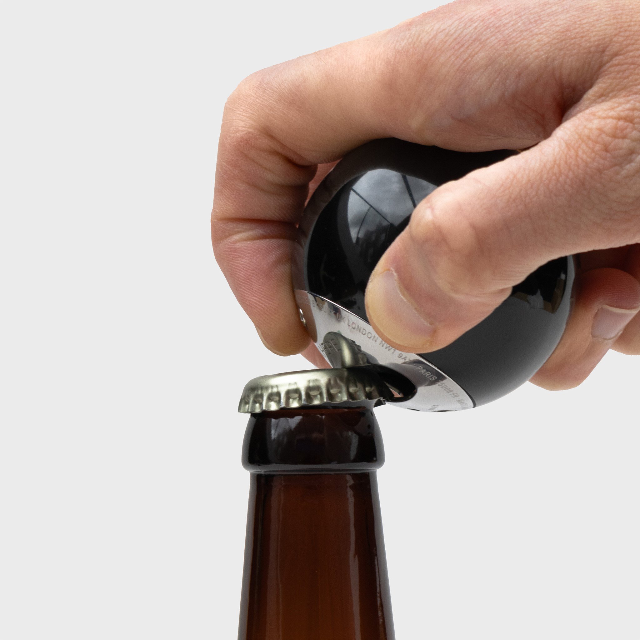 Hand öffnet eine Bierflasche mit dem Billardkugel-Flaschenöffner