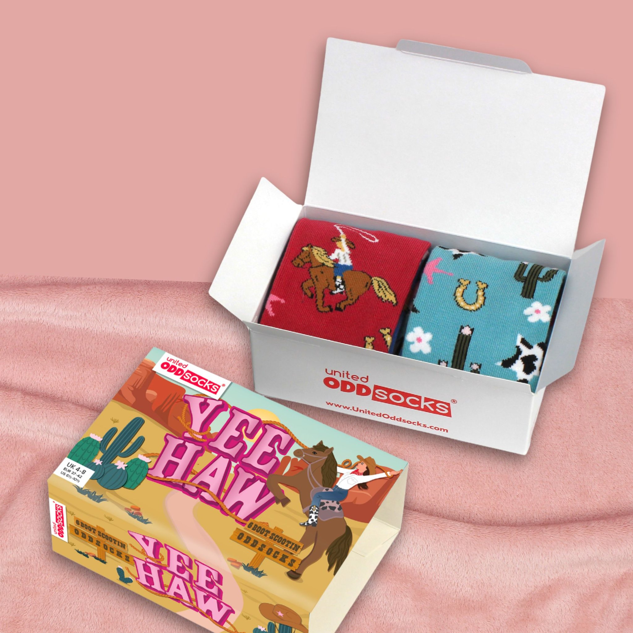 Geöffnete Yee Haw Box mit Socken auf rosa Decke