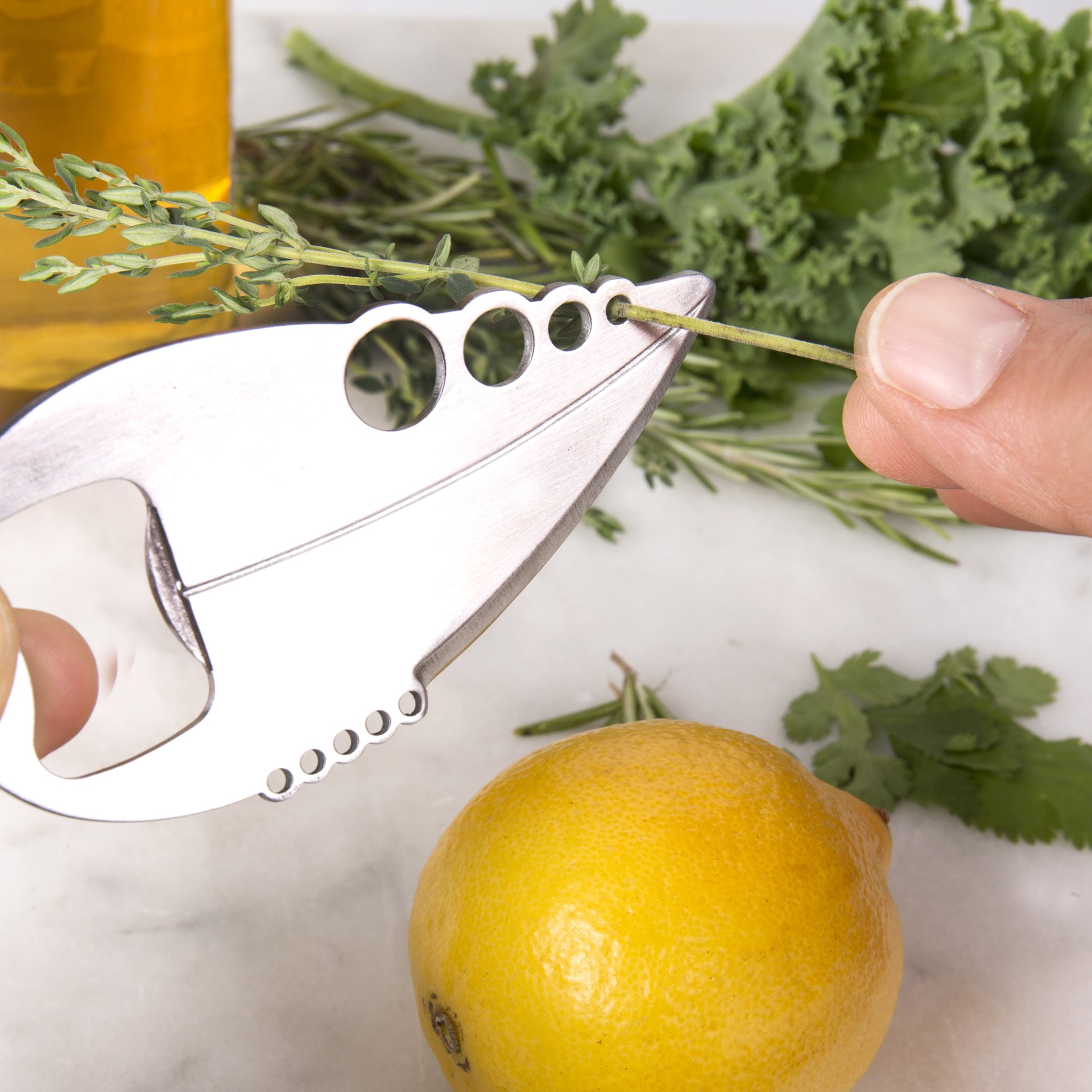 Multi-outil de cuisine effeuillant du thym, citron et herbes à côté