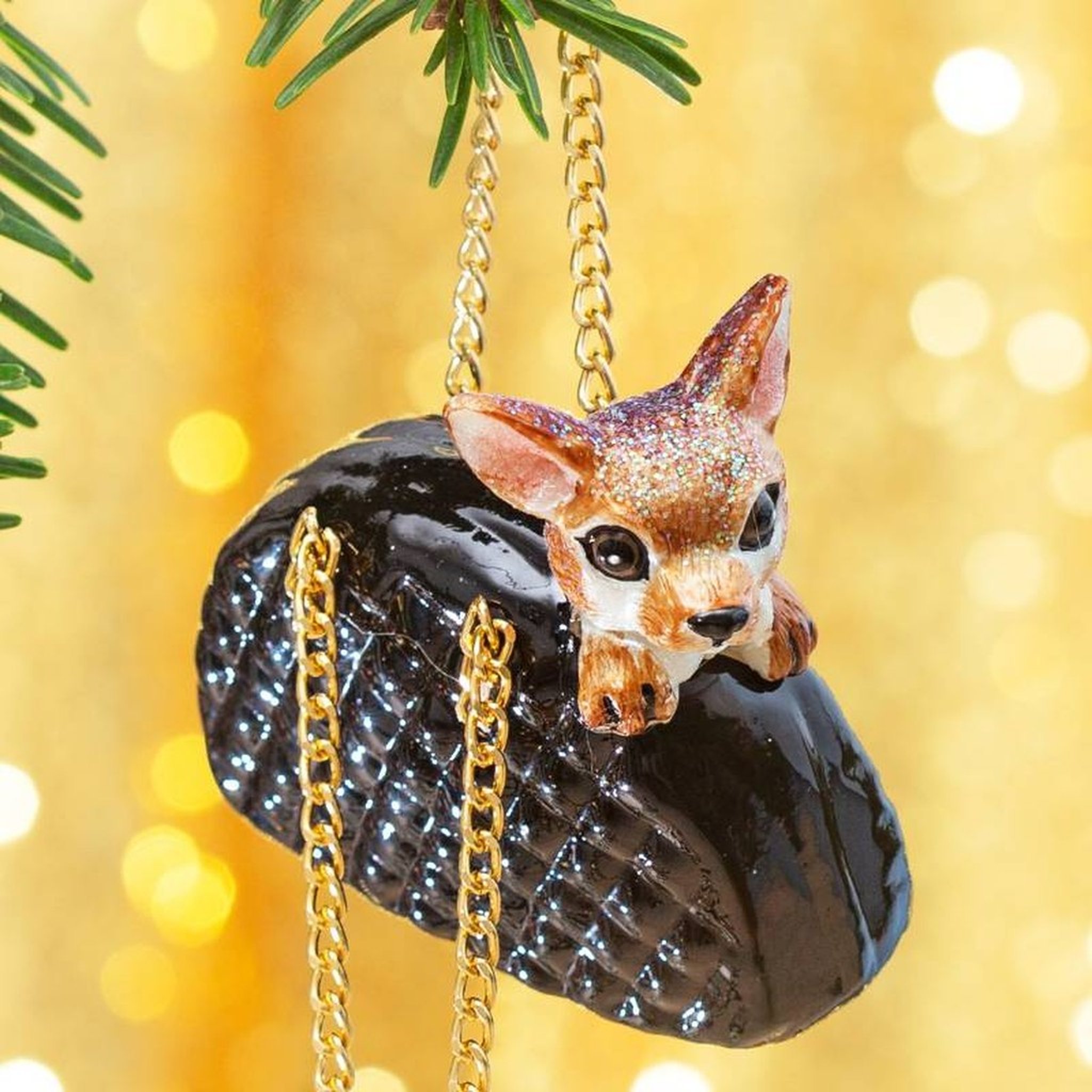 Décoration de sapin chihuahua dans son sac en gros plan sur une branche de sapin