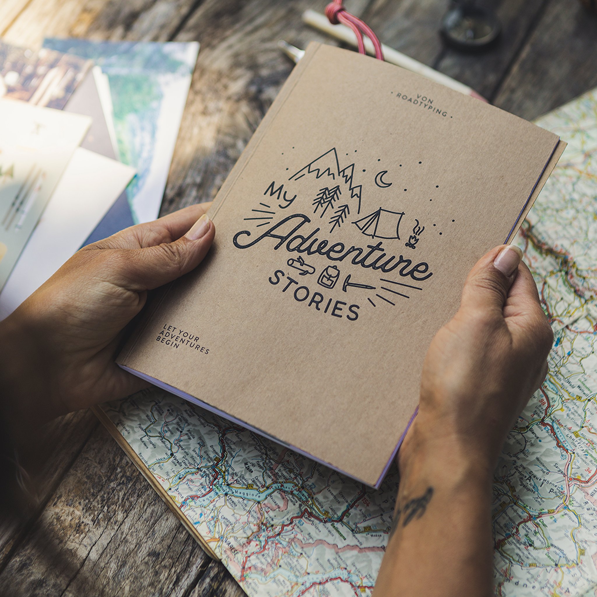 Reisetagebuch My Adventure Stories mit Kraftpapier-Umschlag, ueber einer Landkarte gehalten