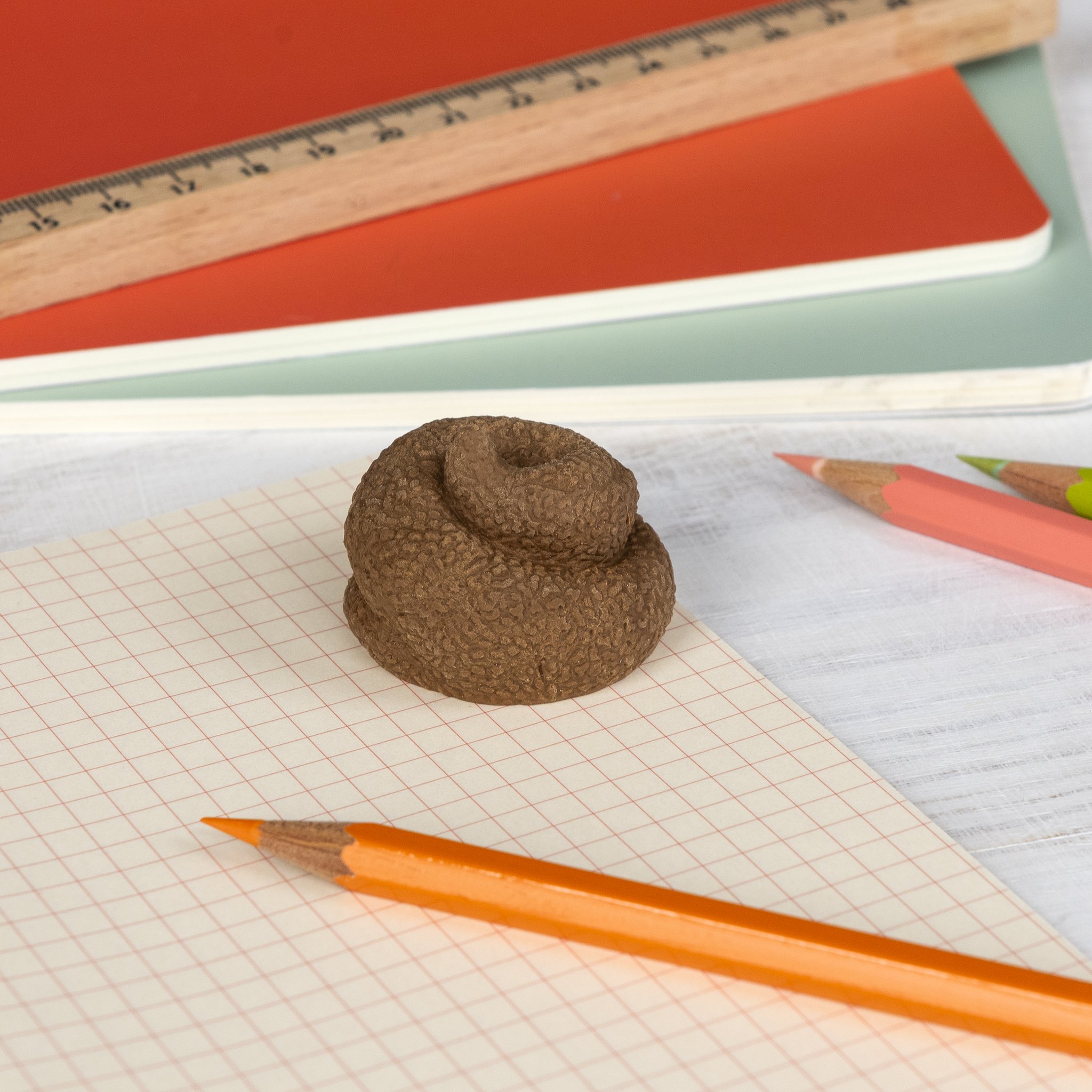 Gomma cacca su un quaderno accanto a matita e righello