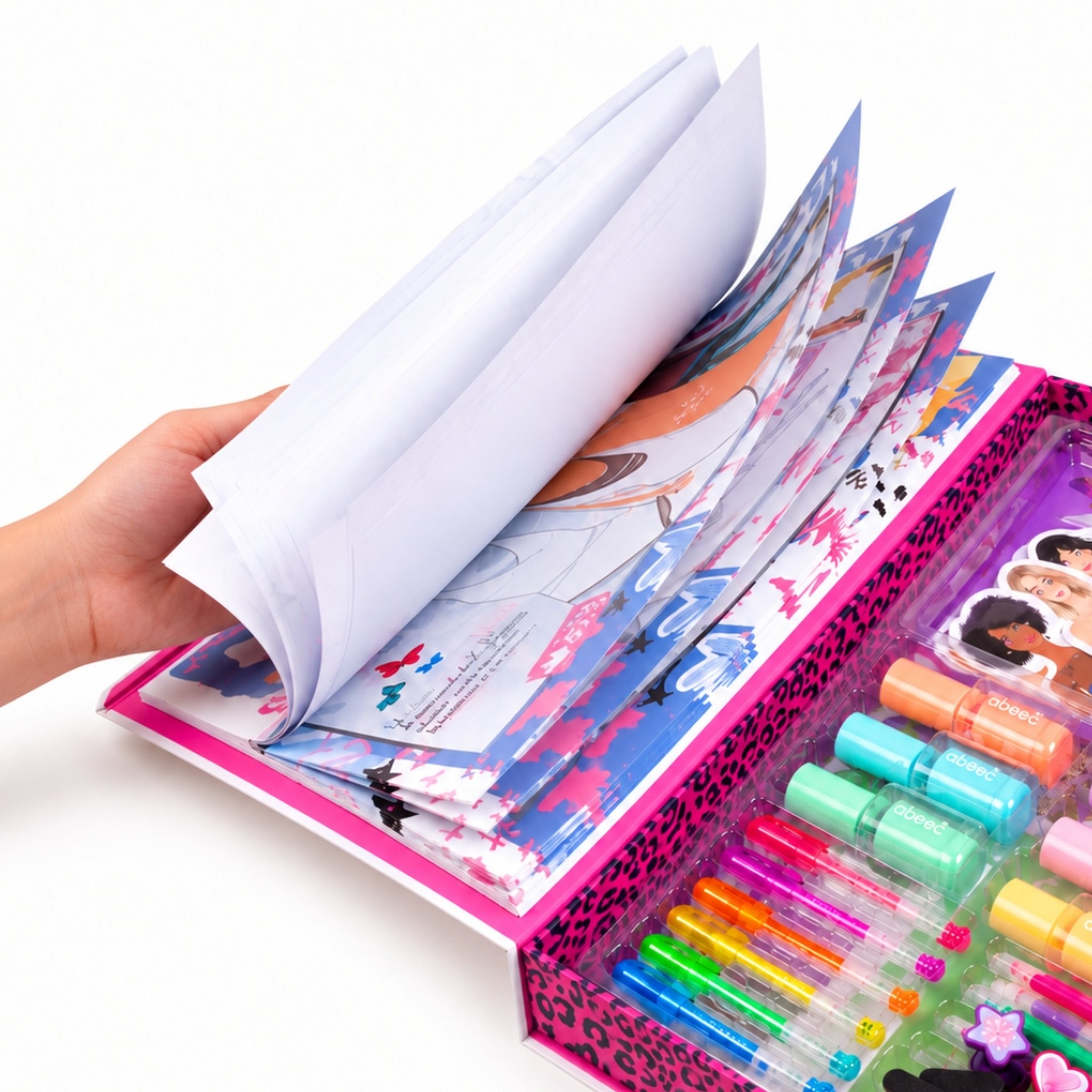 Hand blättert im Zeichenblock des Modedesigner-Sets, daneben die Stifte in der Box