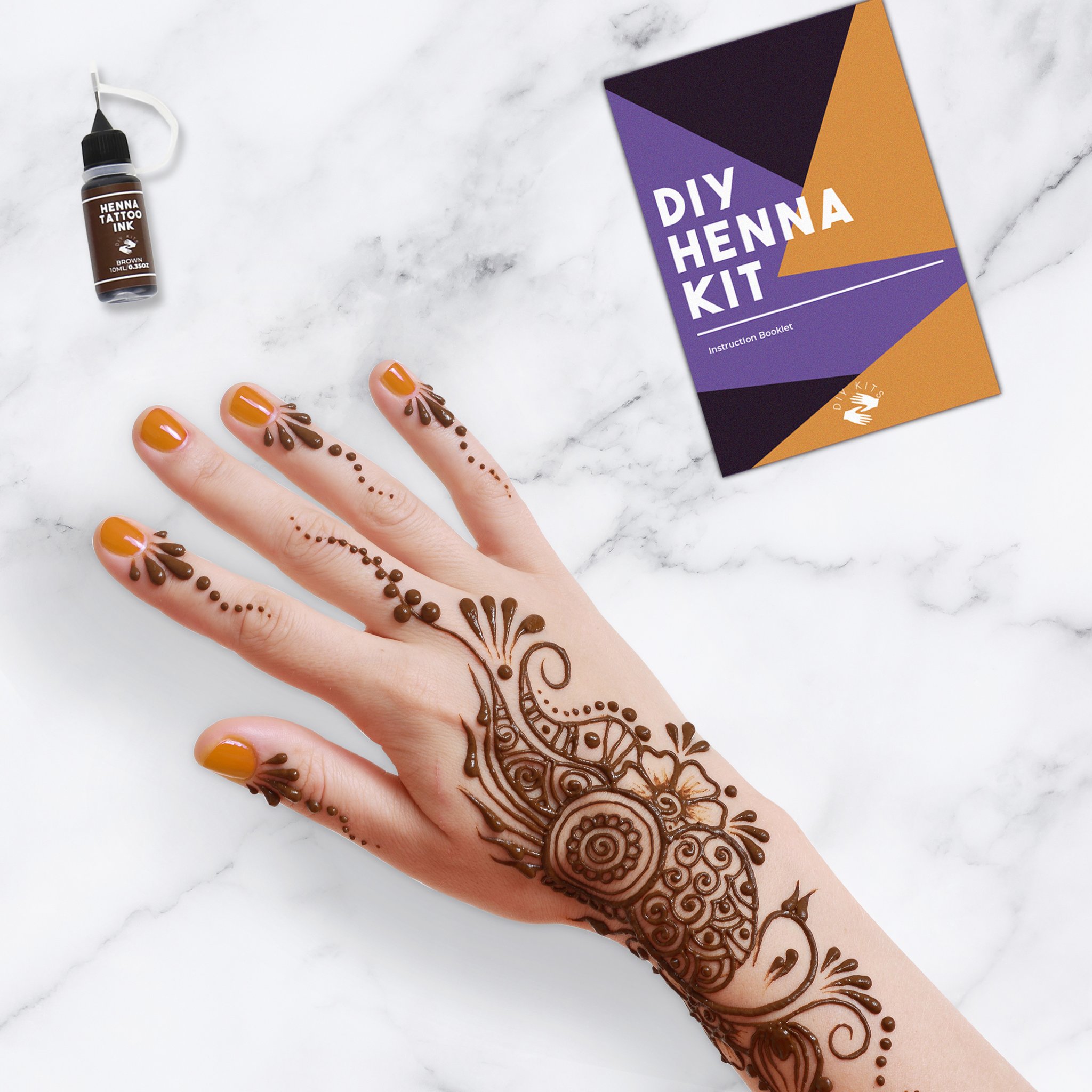 Hand mit Henna-Muster neben dem Fläschchen und der Dose des DIY Henna-Sets
