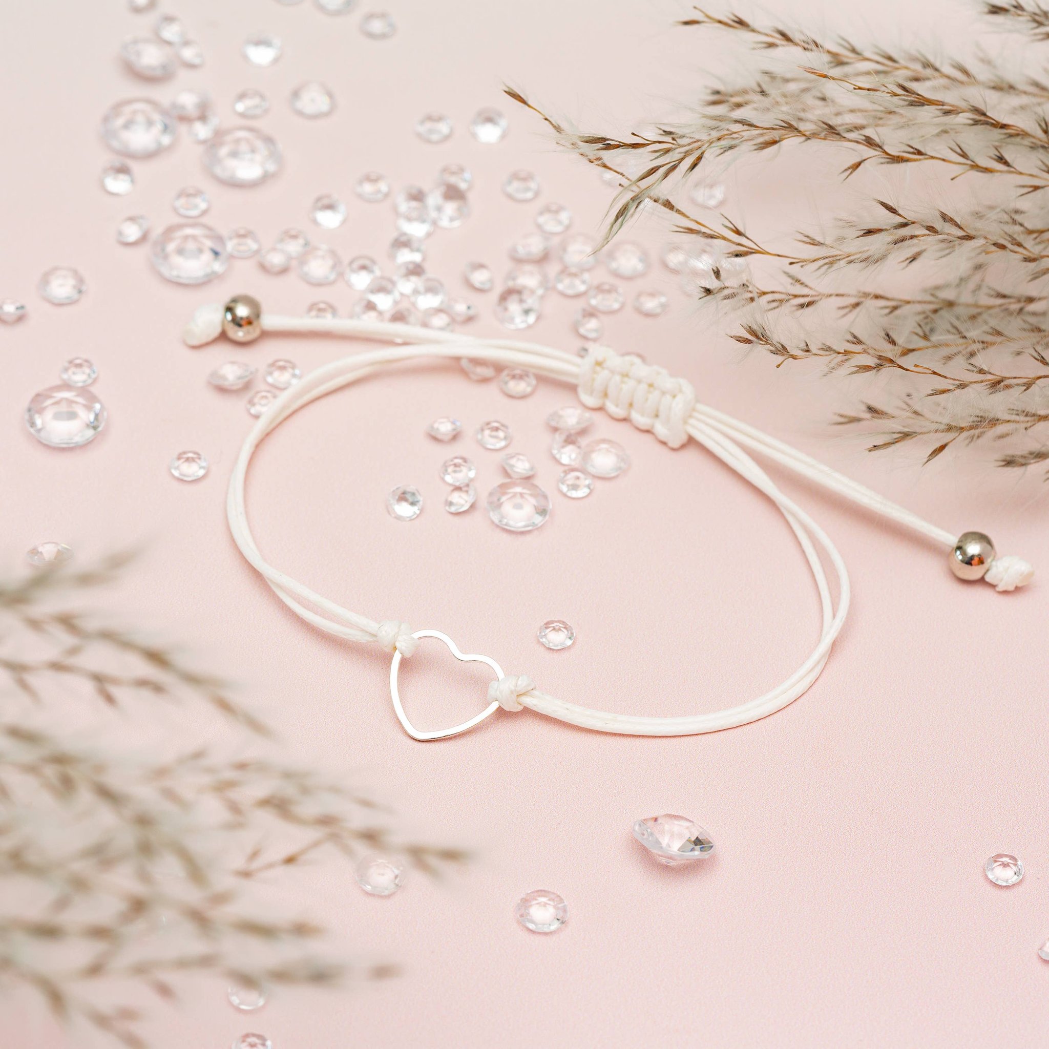 Ausgelegtes Happy-Birthday-Armband mit Herz und Zugband auf rosa Grund mit Glassteinen