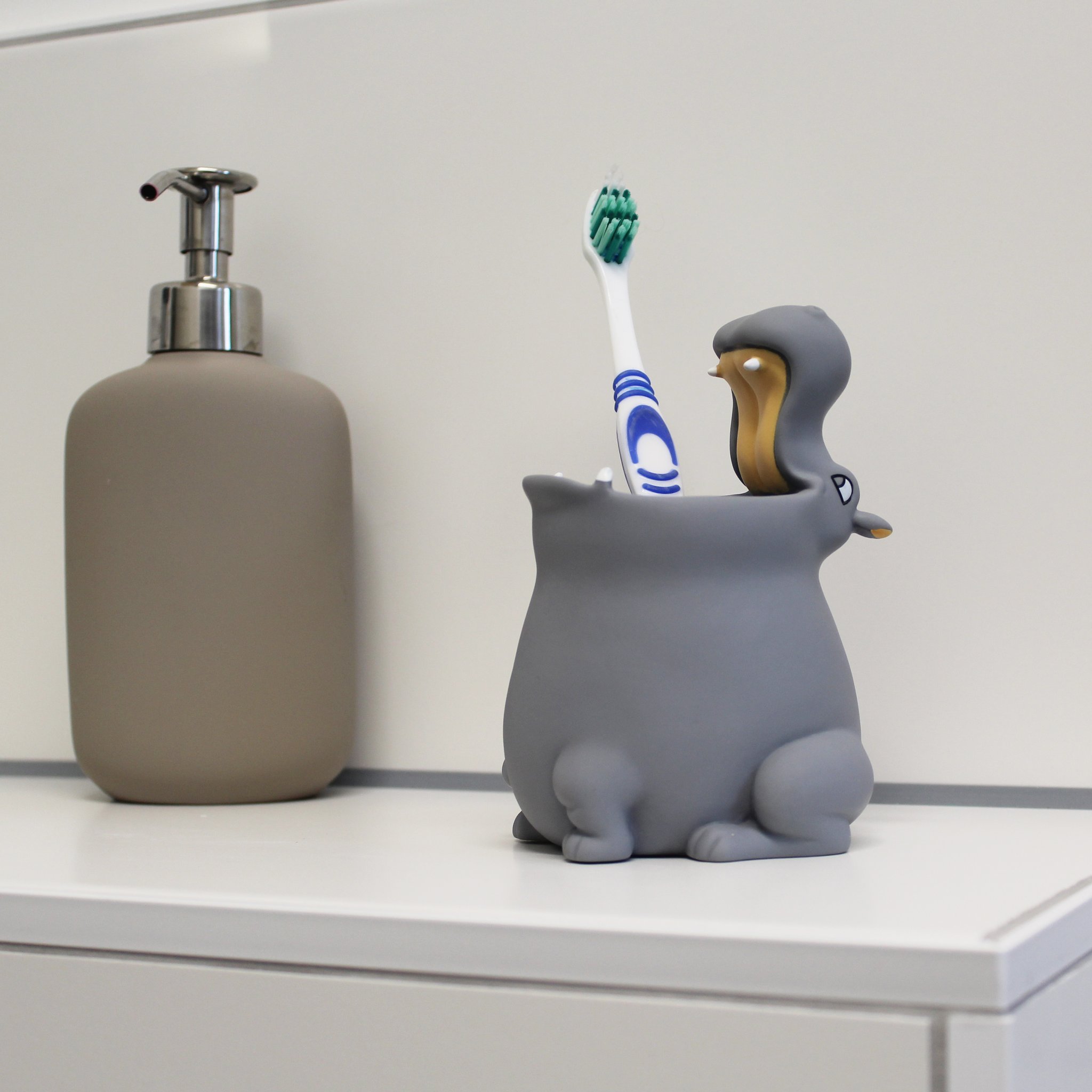Hippo toothbrush tumbler next to a soap dispenser in the bathroom