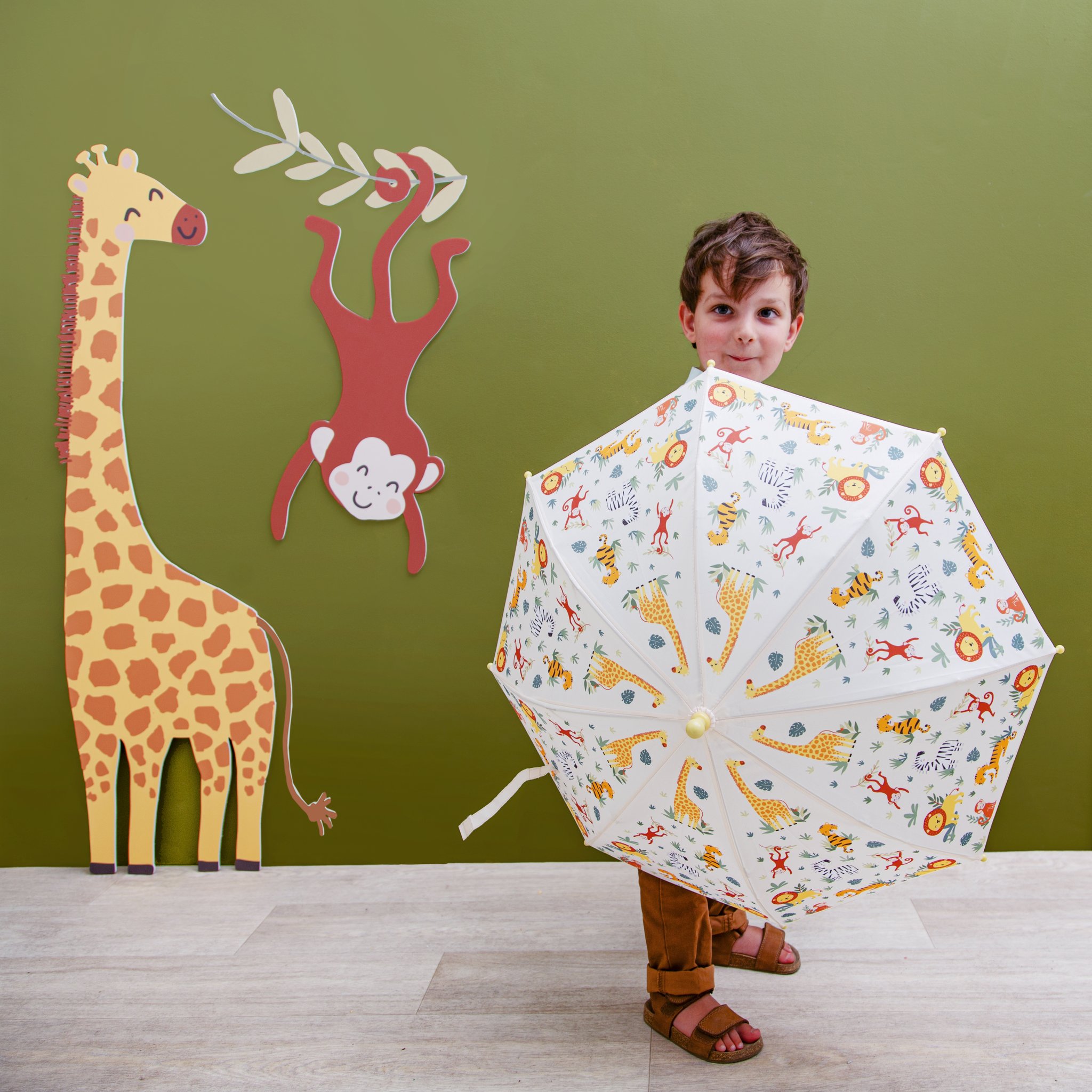 Savannah safari kids umbrella by Sass & Belle, child with umbrella in front of giraffe and monkey