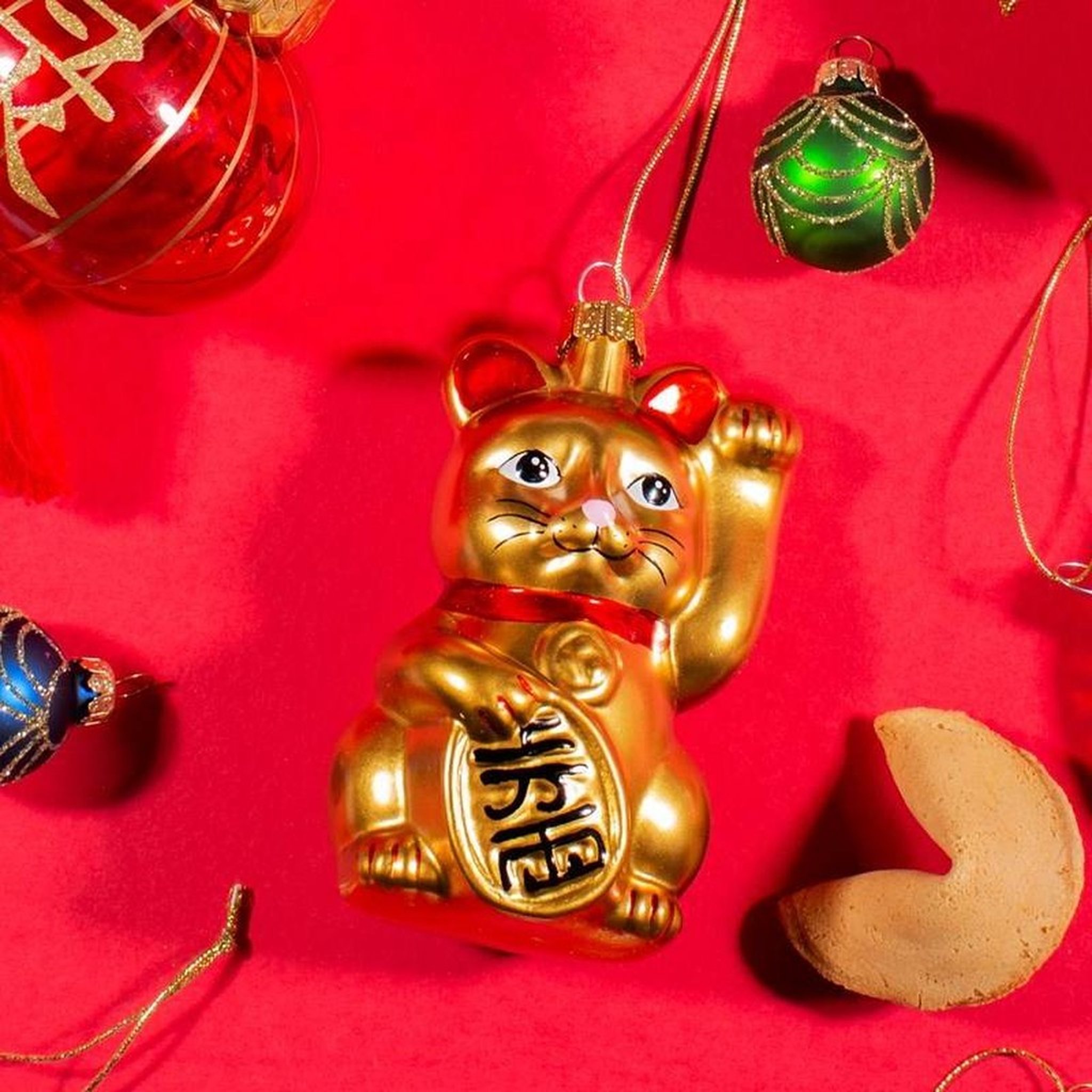 Décoration de sapin chat porte-bonheur en gros plan avec biscuit chinois sur fond rouge