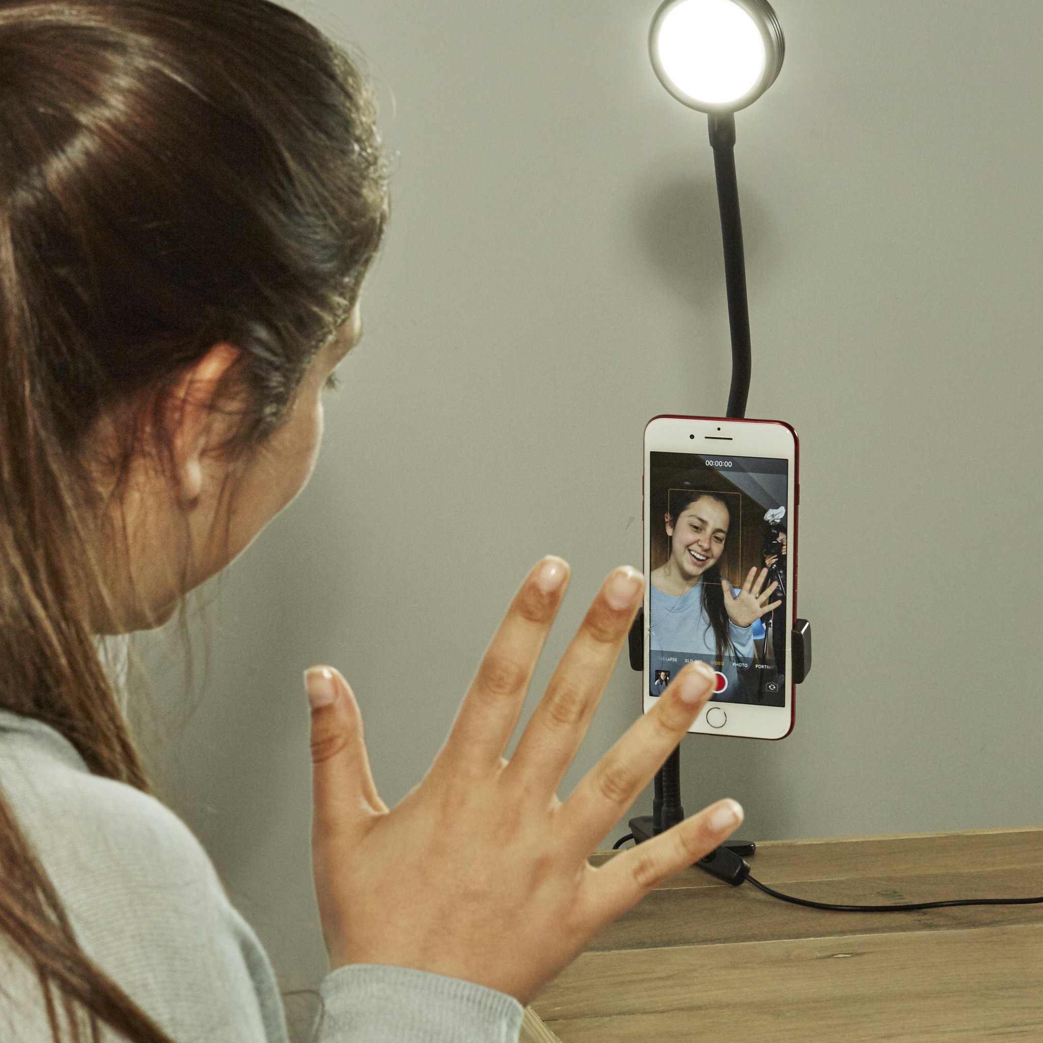 Woman waving at the smartphone in the live streaming kit with ring light