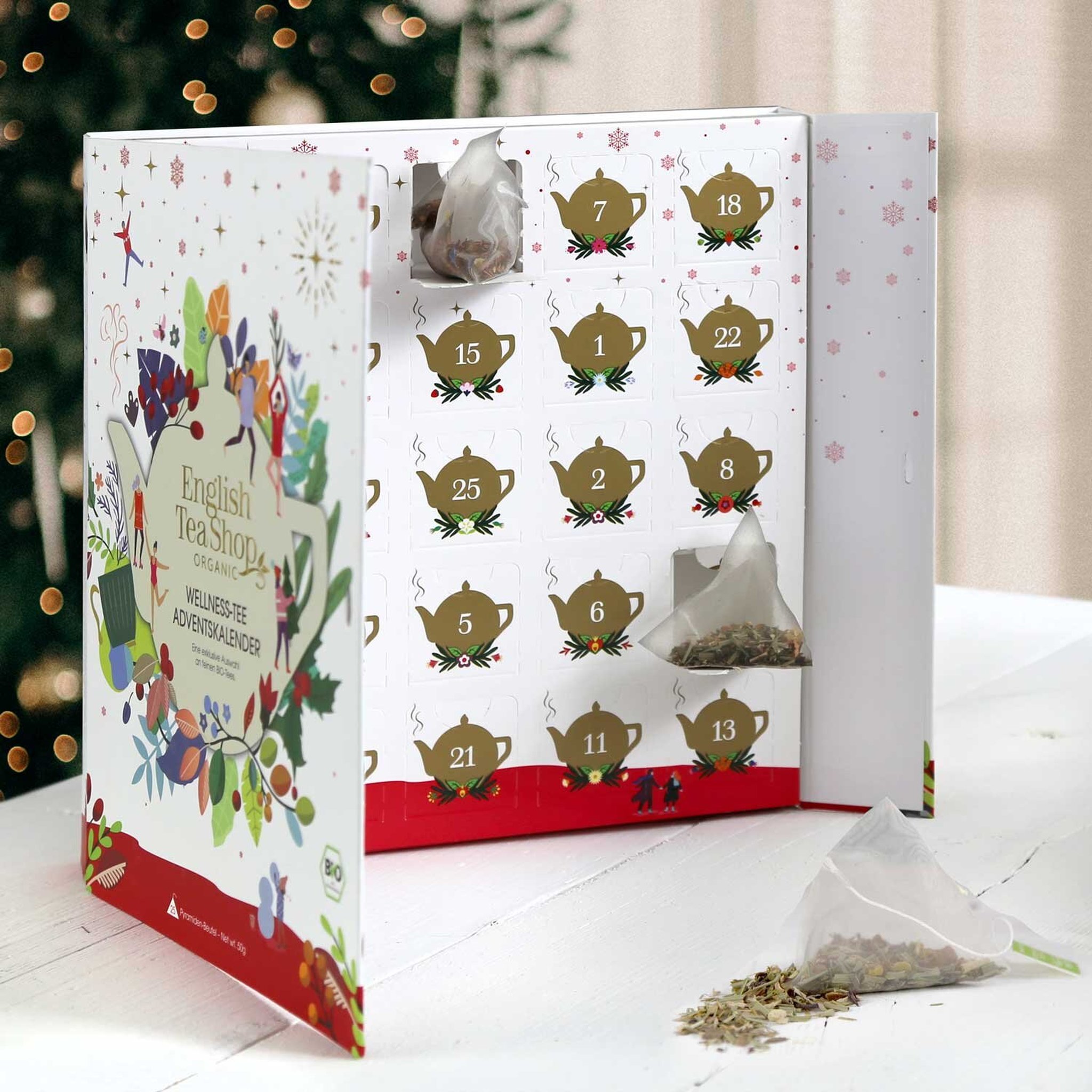 Aufgeklappter Bio-Tee-Adventskalender mit Teekannen-Türchen und einem Pyramidenbeutel davor
