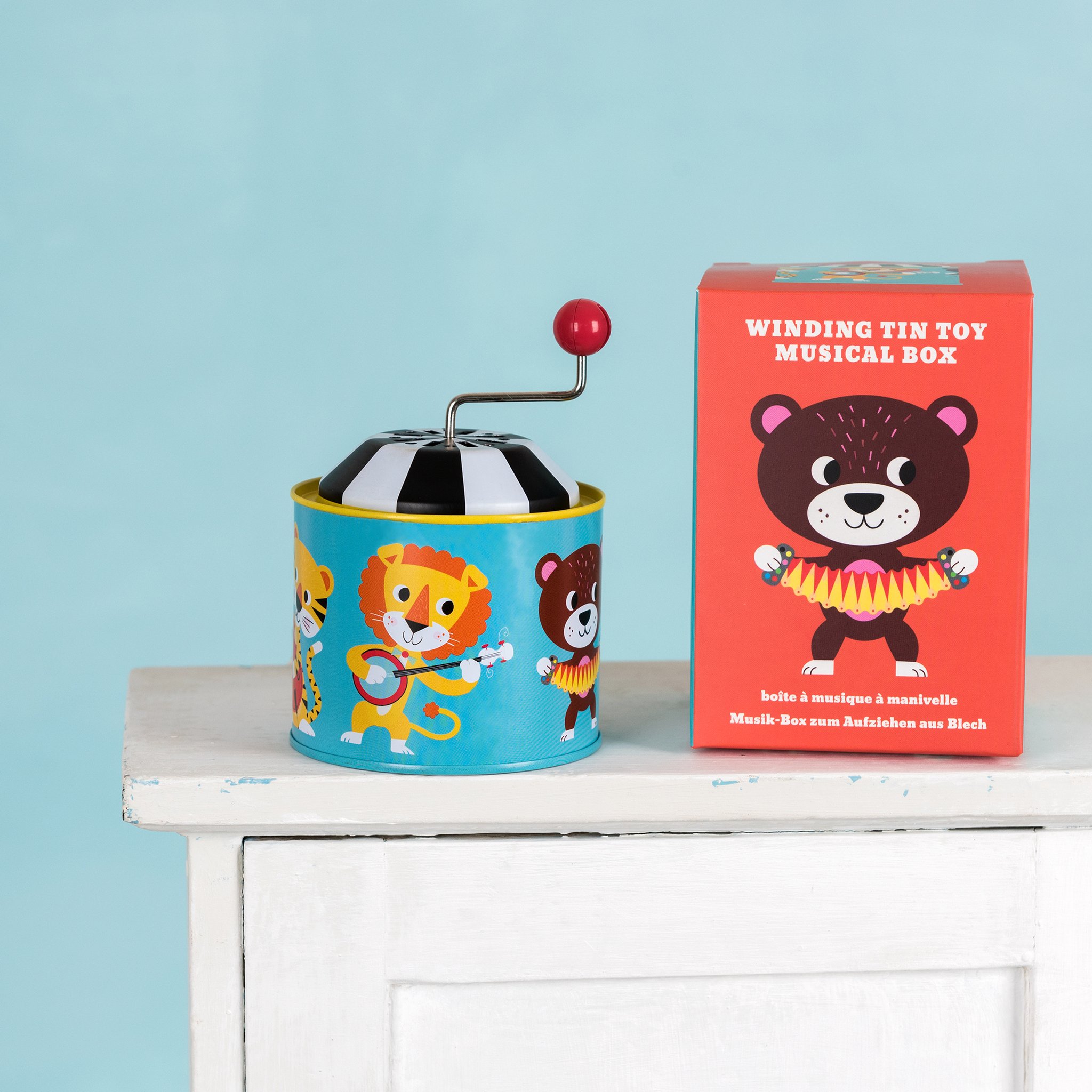 Animal Park tin musical box with red handle next to the box on the cabinet