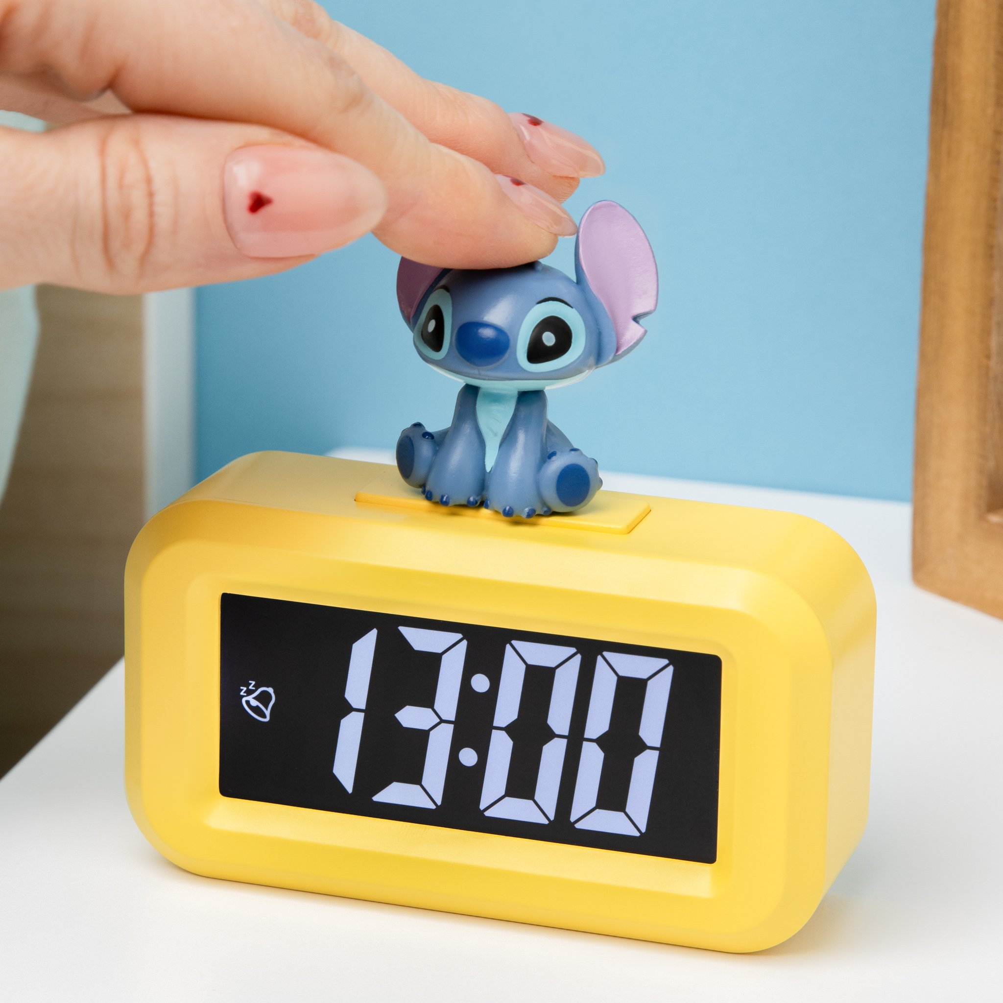 Finger tippt auf die Stitch-Figur des Weckers