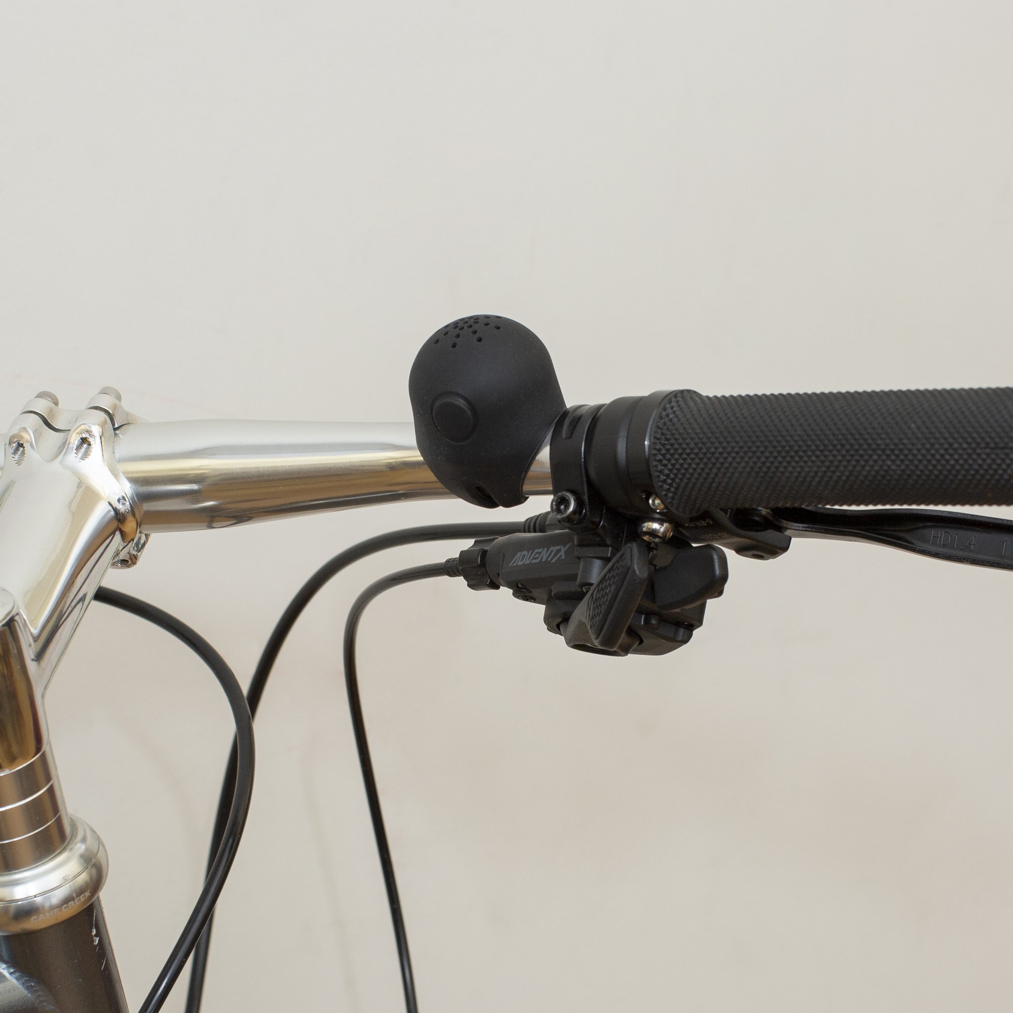 Schwarze elektronische Fahrradklingel neben dem Griff am silbernen Lenker