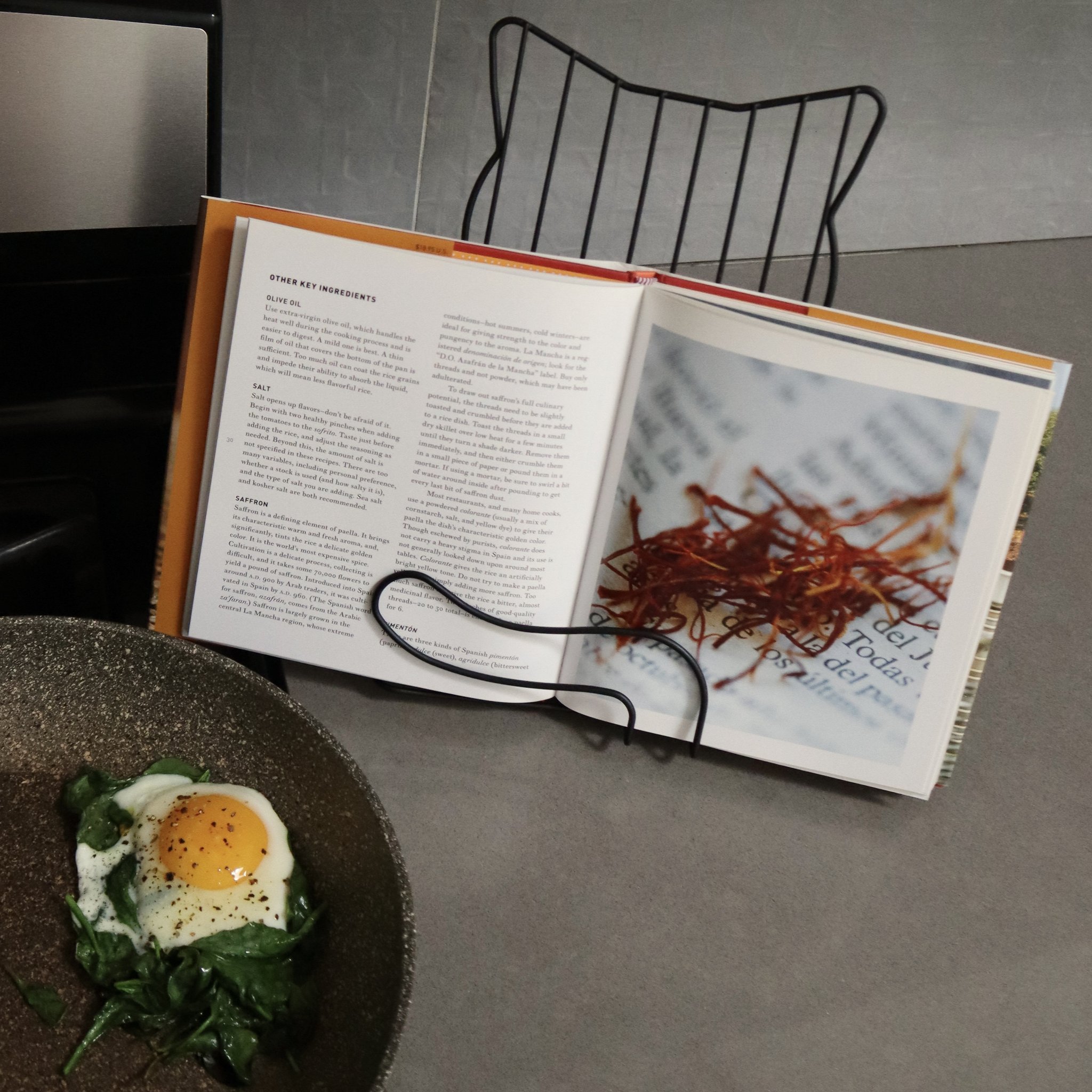 Porte-livre chat tenant un livre de cuisine près de la poêle