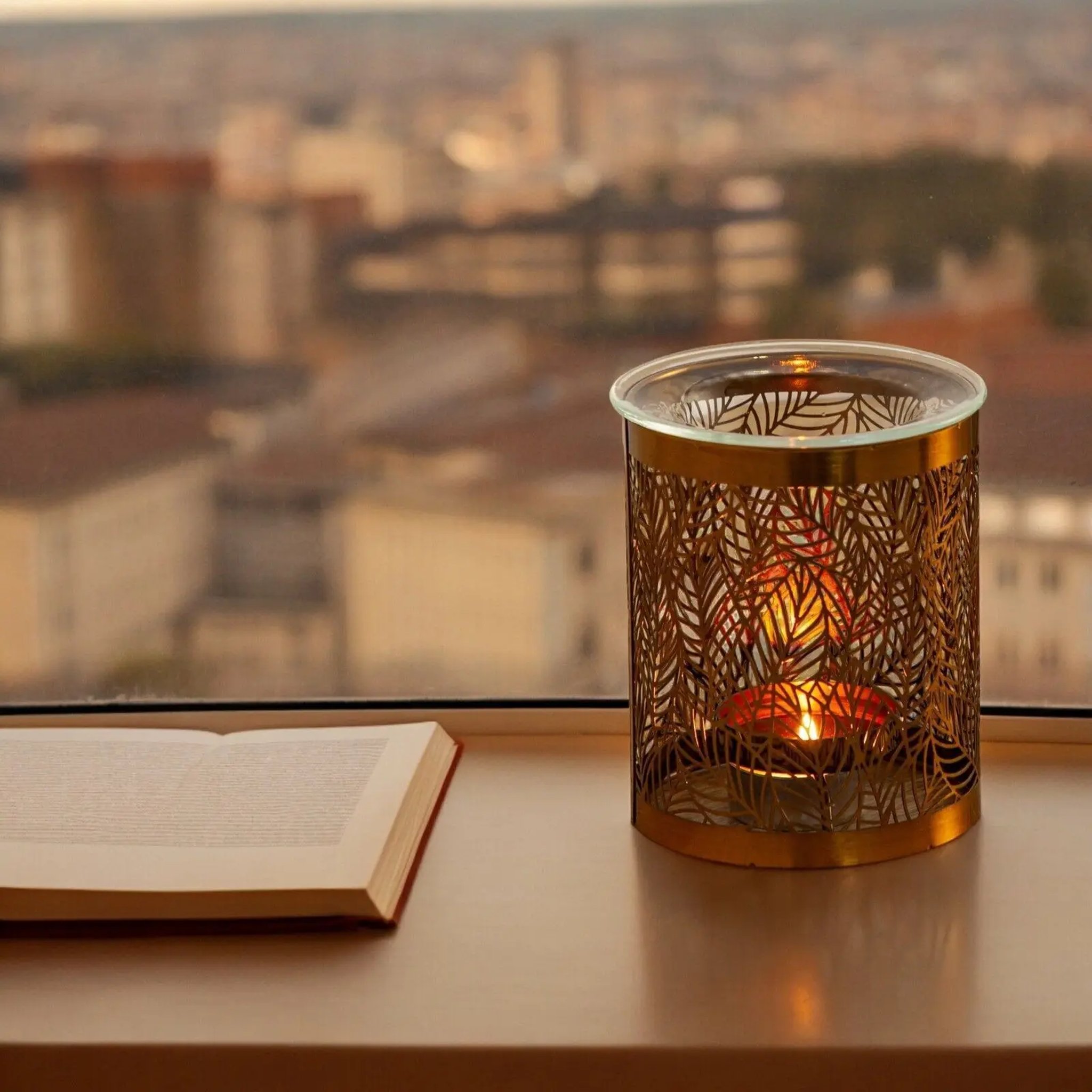 Leaf pattern oil burner by the window next to an open book