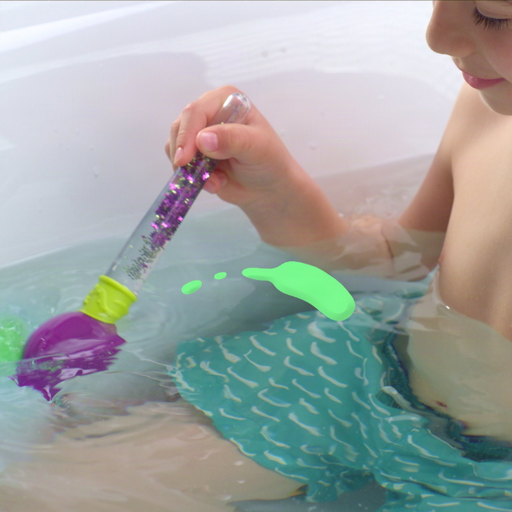 Child painting green colour in the bath water with the brush