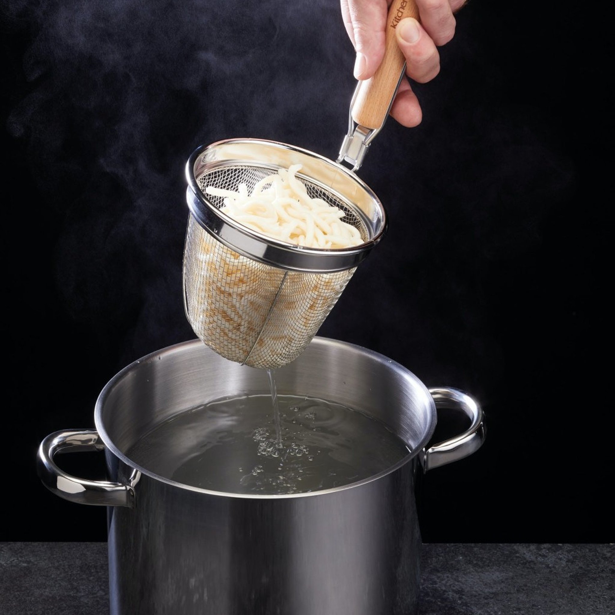 Mano che solleva lo scolapasta con le tagliatelle