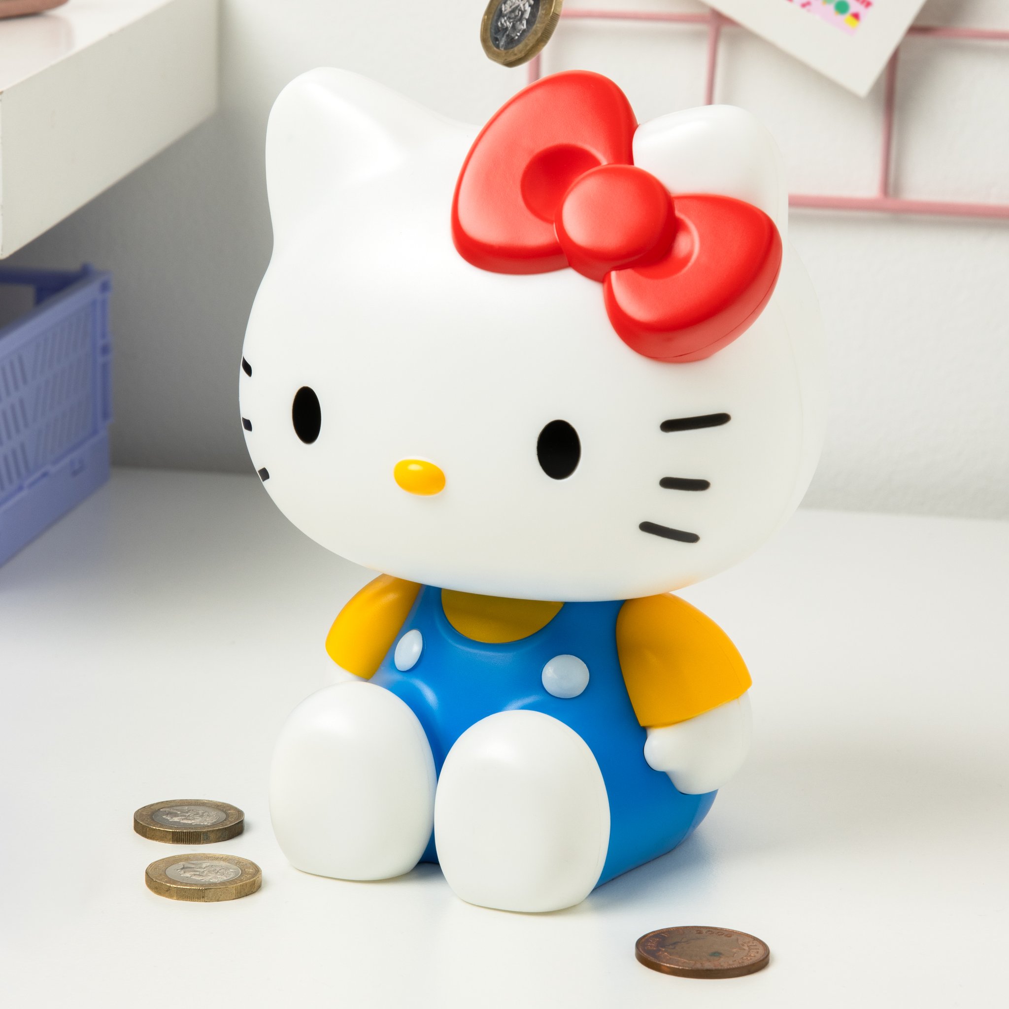 Hello Kitty money box with coins on a light surface