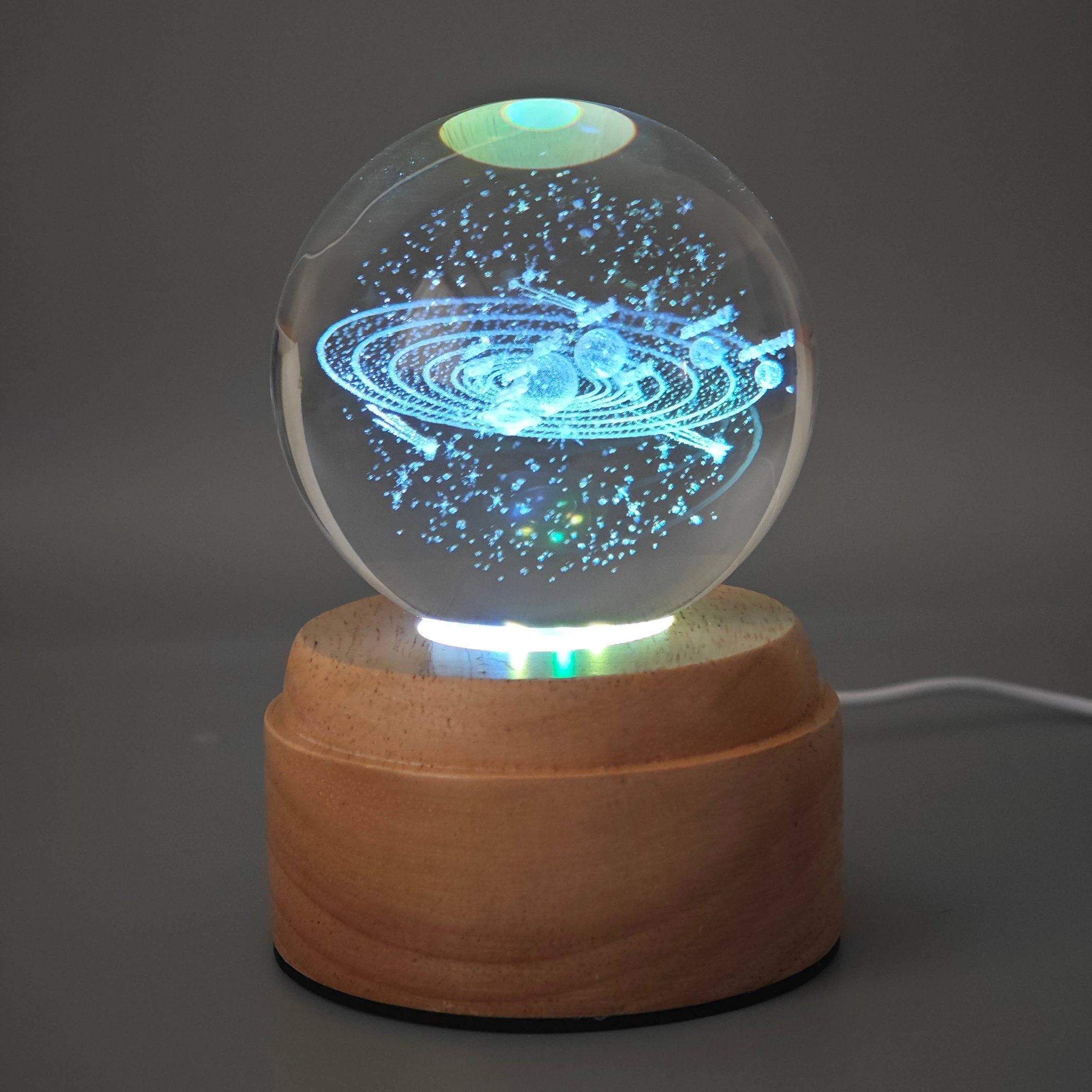 Solar system crystal ball on its wooden base with the USB cable connected