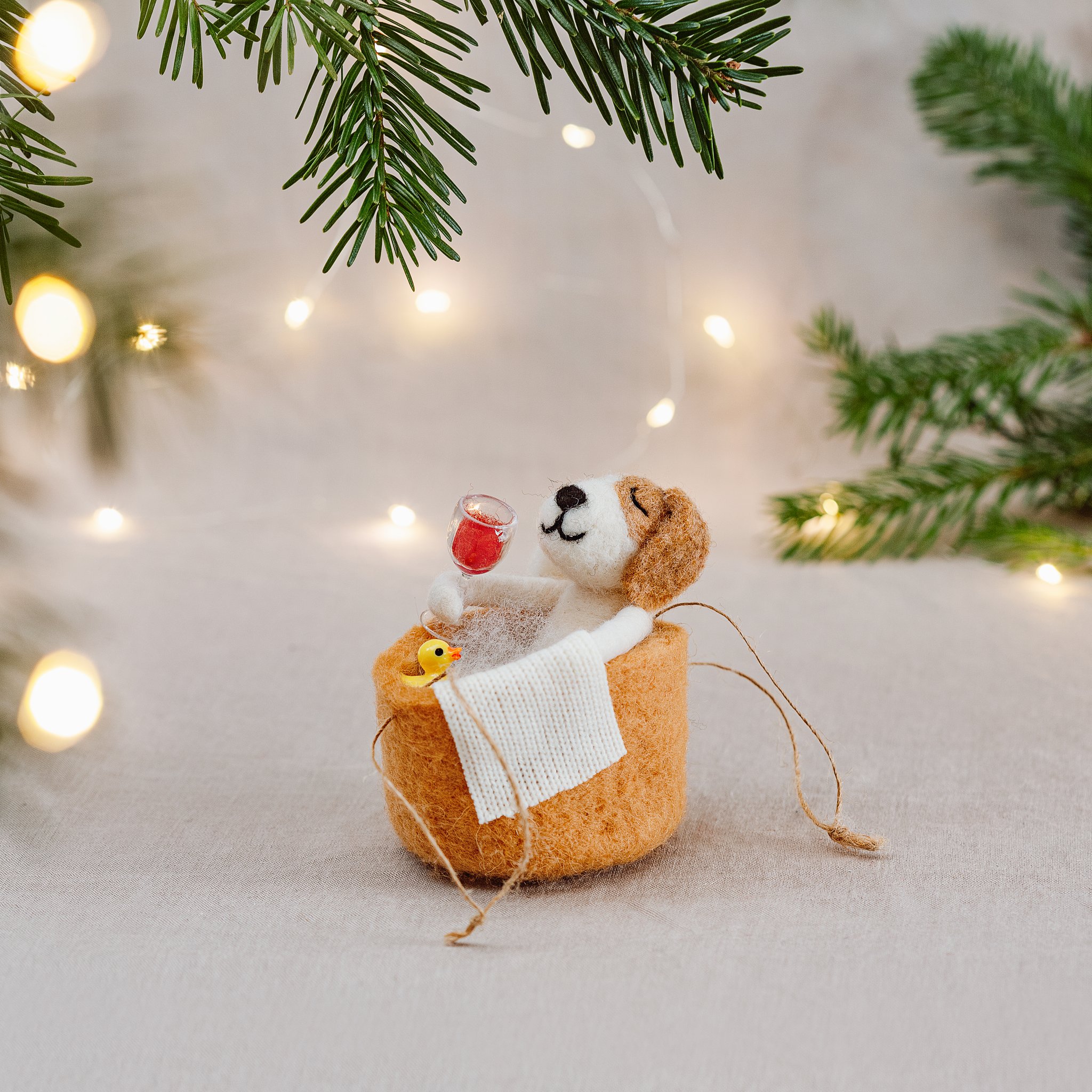 Décoration de Noël chien dans le bain Sass & Belle, chien en feutrine dans une baignoire avec verre de vin et canard sur une branche de sapin