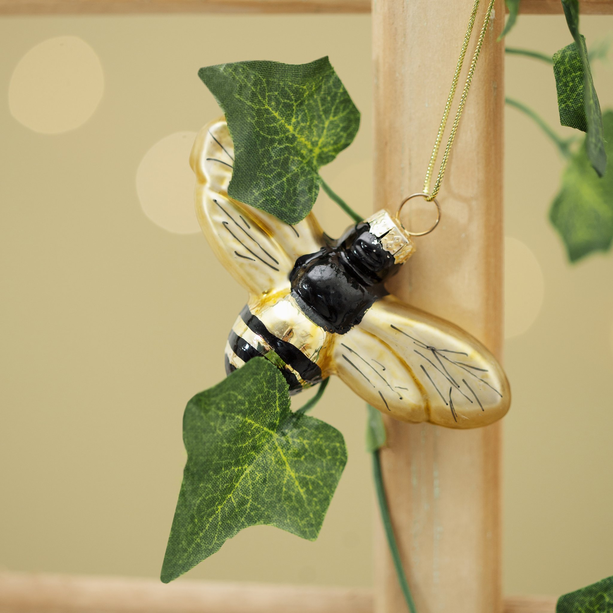 Bee with golden wings hanging among ivy leaves on a wooden trellis