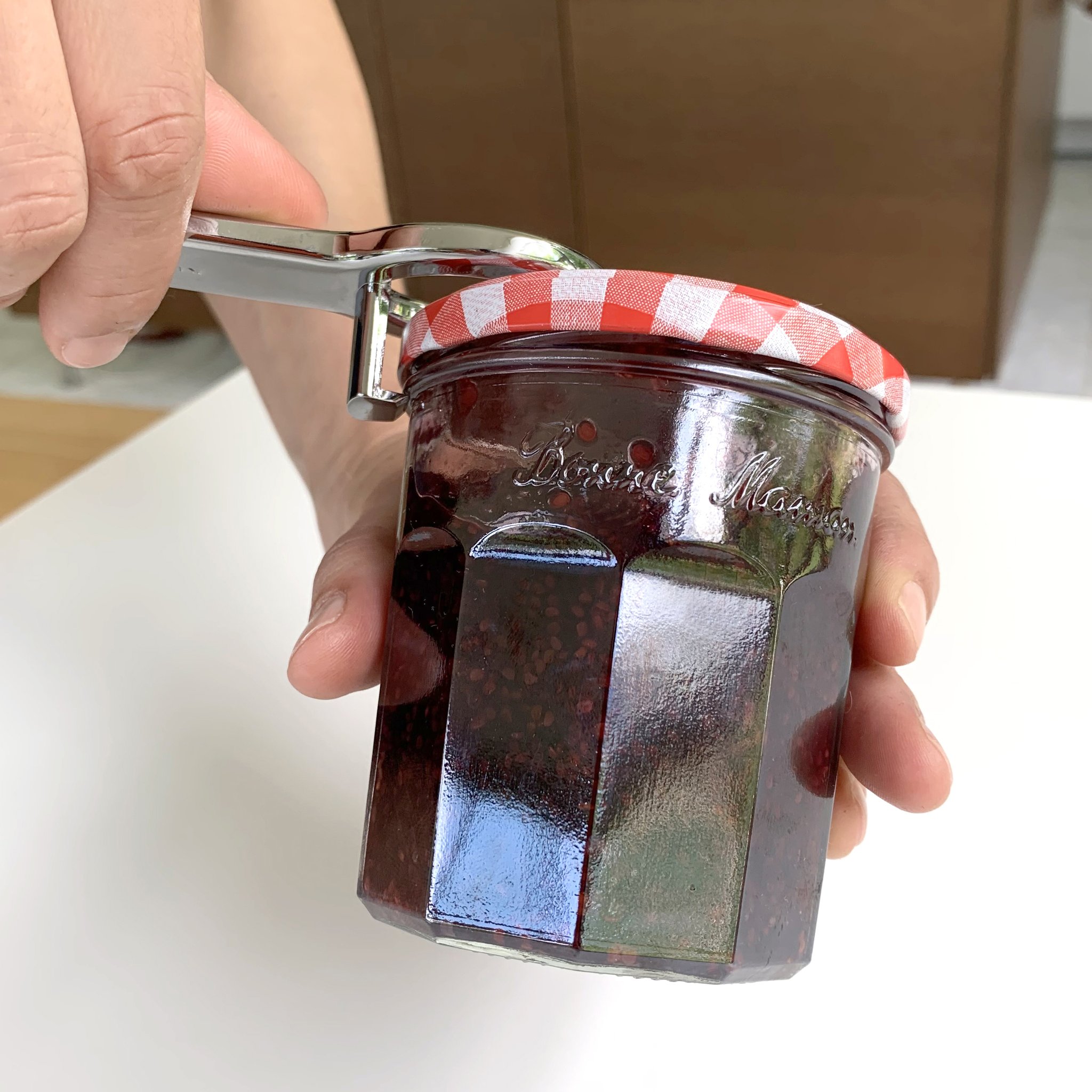 Ouvre-bocal et bouteille soulevant le couvercle d'un pot de confiture
