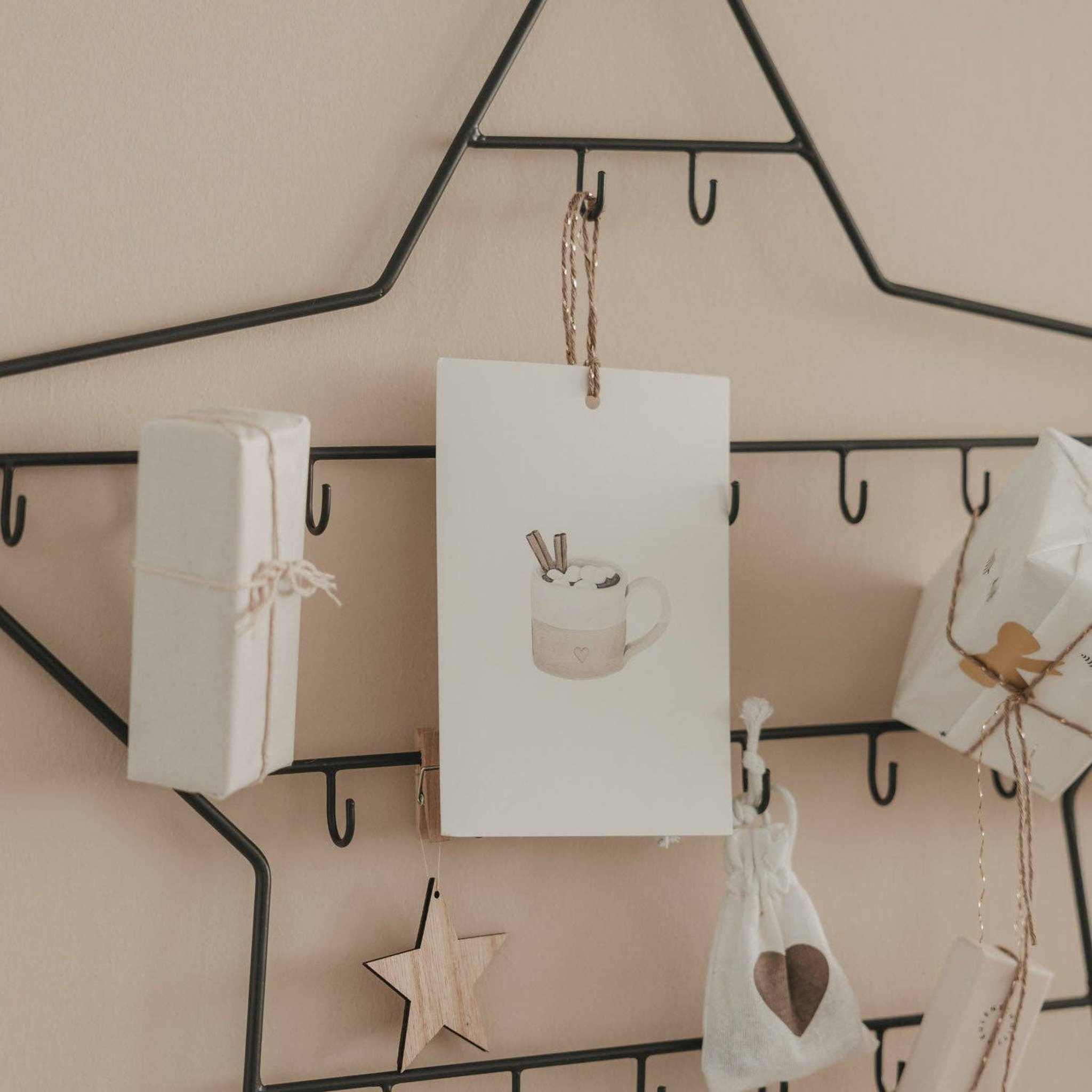 Close-up of the hooks on the metal star with a card, white parcels and a wooden star