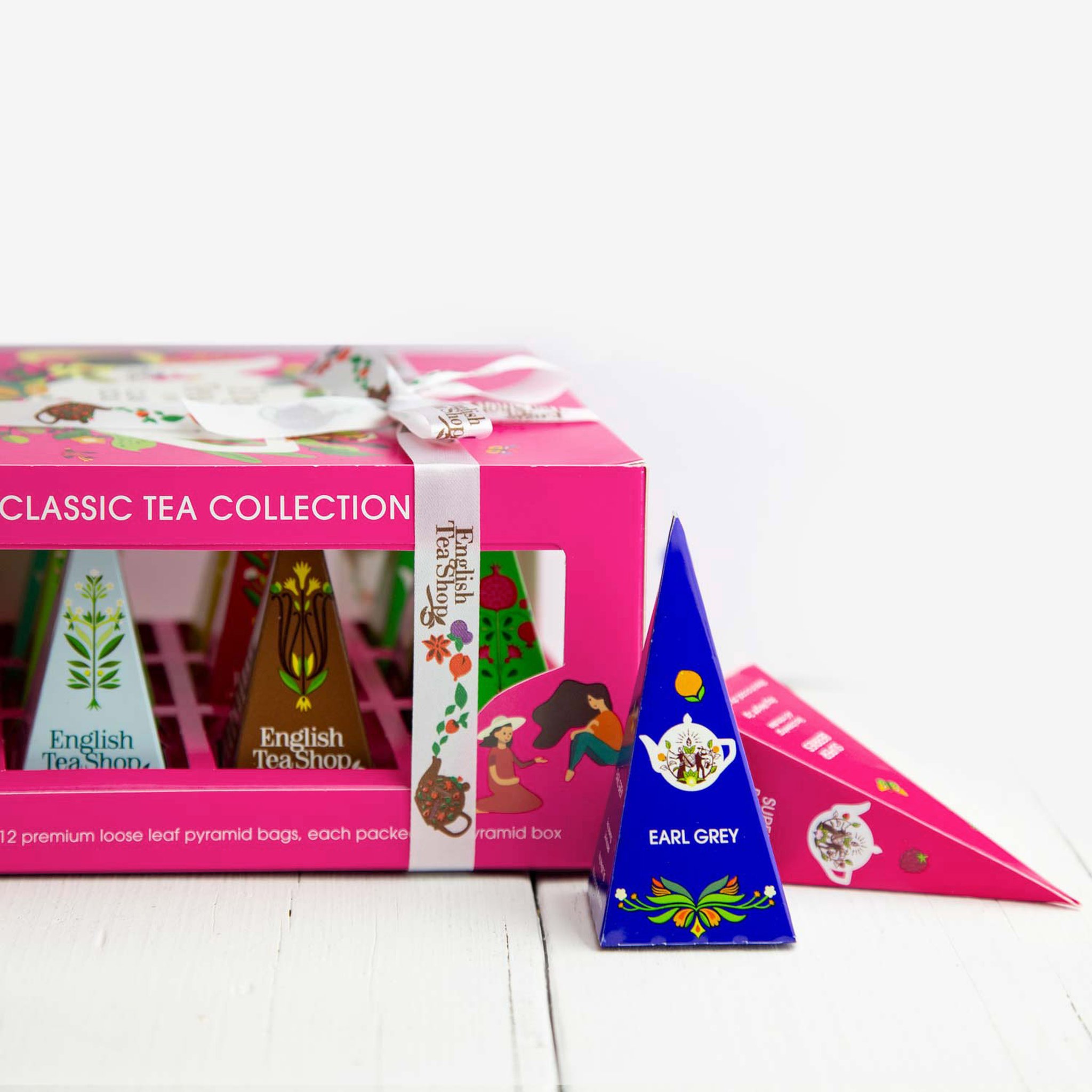 Confezione di tè rosa su legno chiaro, davanti una piramide blu Earl Grey