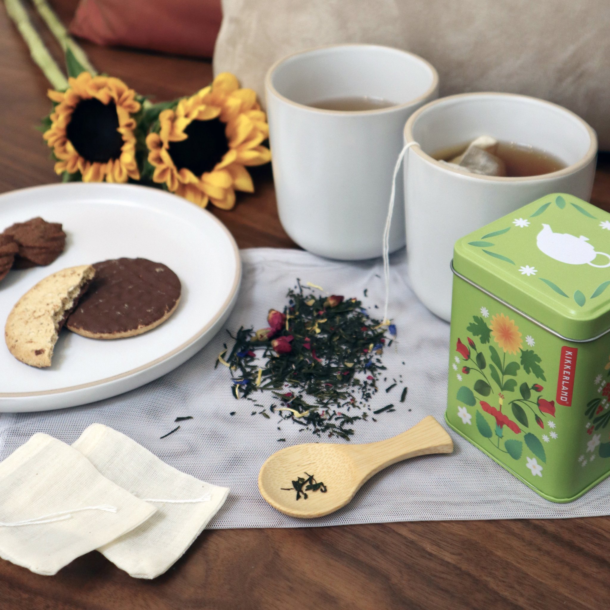 Set Make Your Own Tea avec boîte à thé, tasses, biscuits et tournesols sur la table