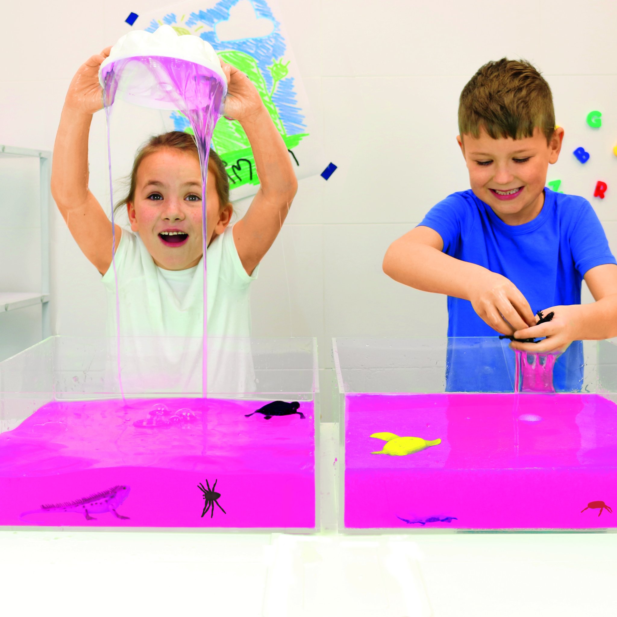 Two children playing in tubs full of pink glitter slime