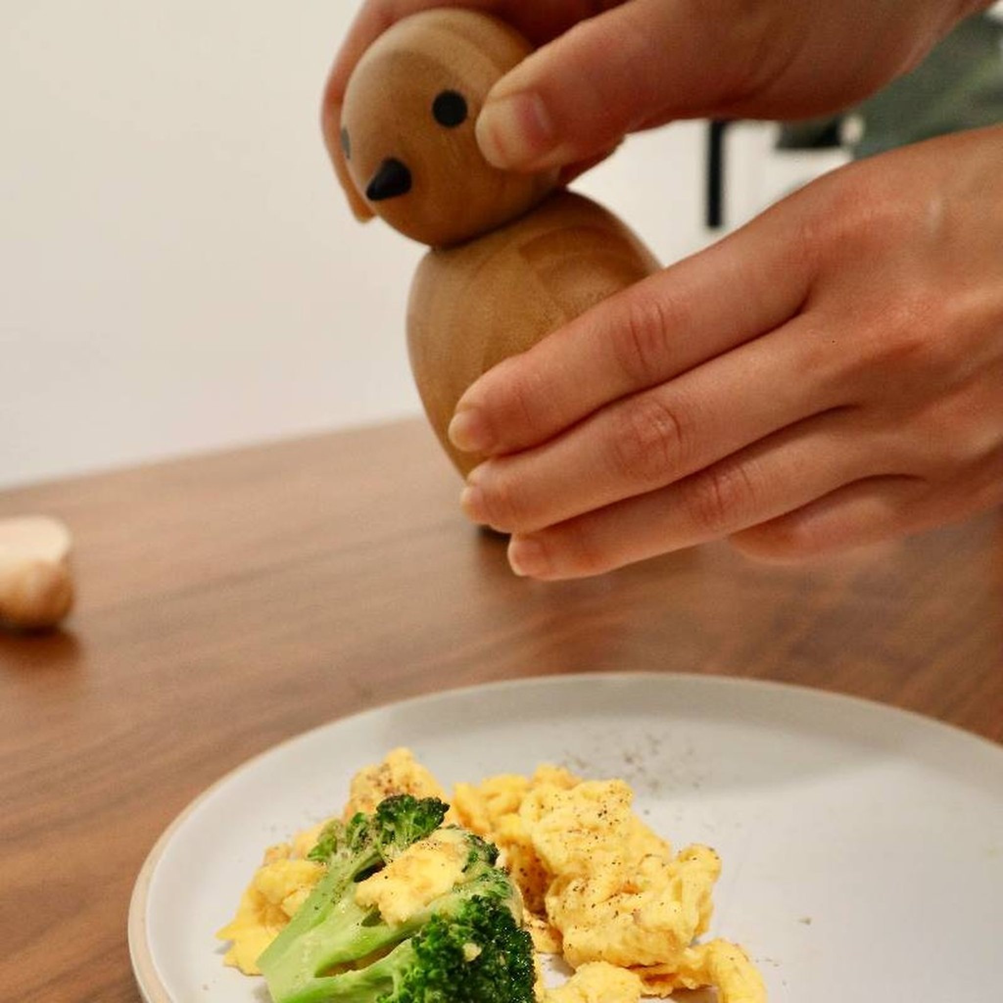 Hand dreht den Kopf der Birdy-Mühle über dem Teller