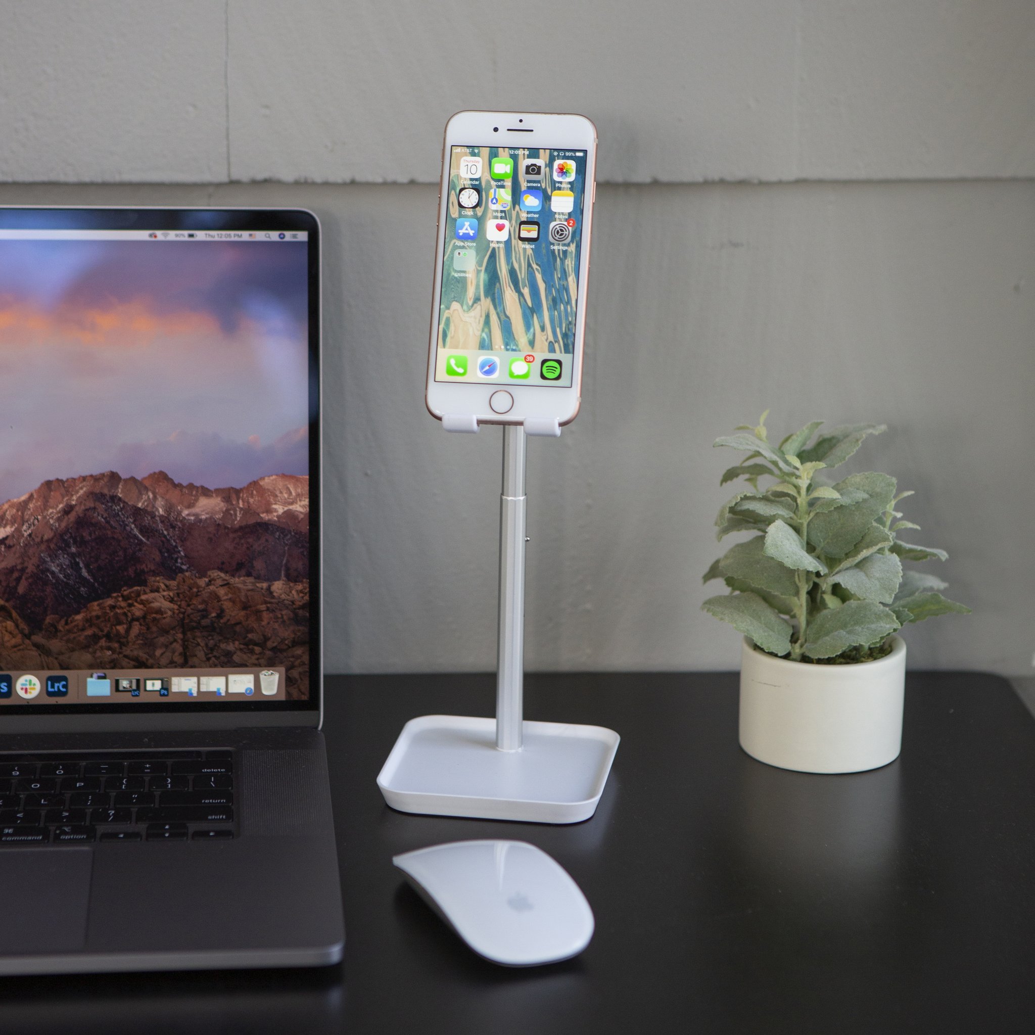 Smartphone-Halter mit Handy auf dem Schreibtisch neben Laptop und Pflanze