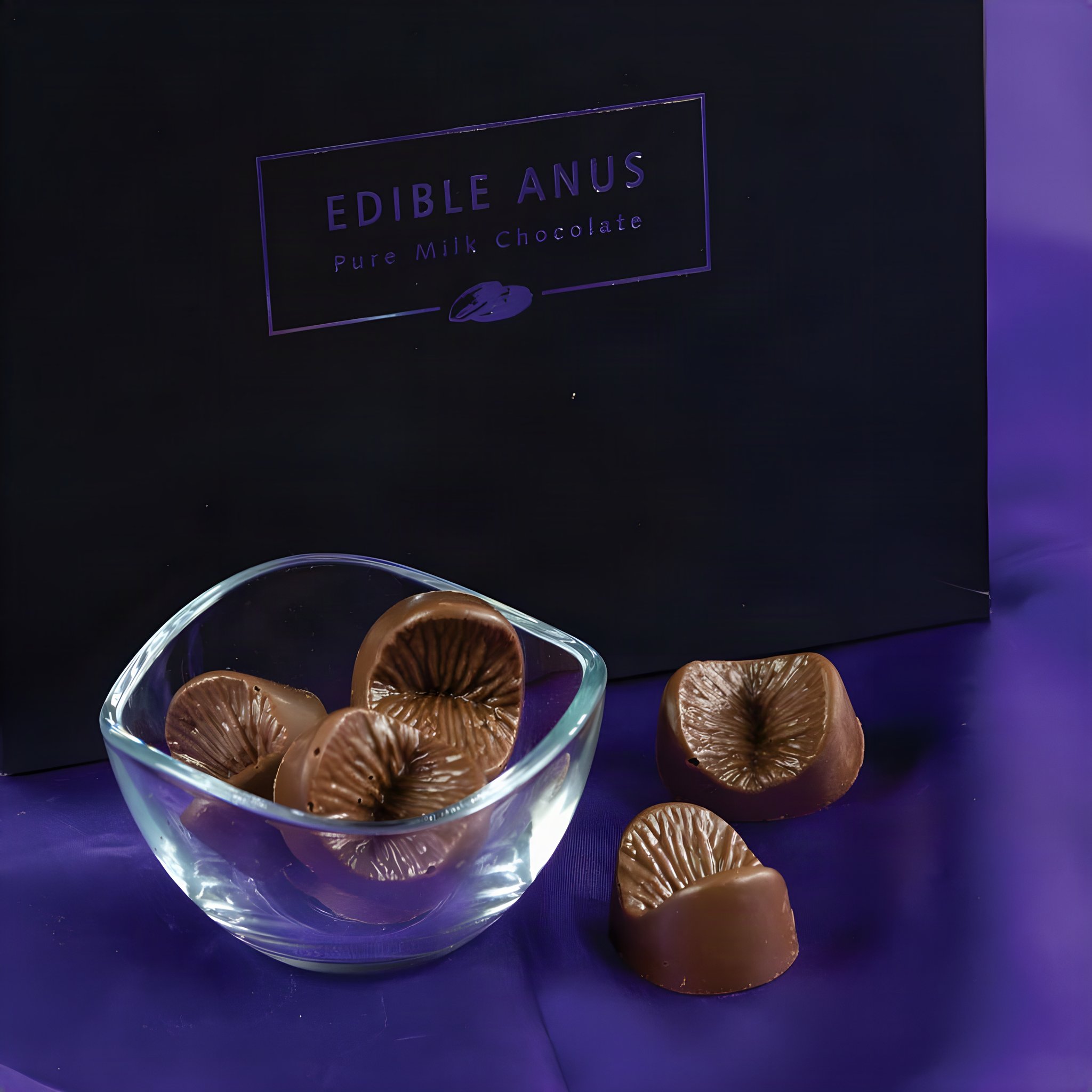 Praline a forma di ano al cioccolato al latte in una ciotola di vetro davanti alla scatola nera