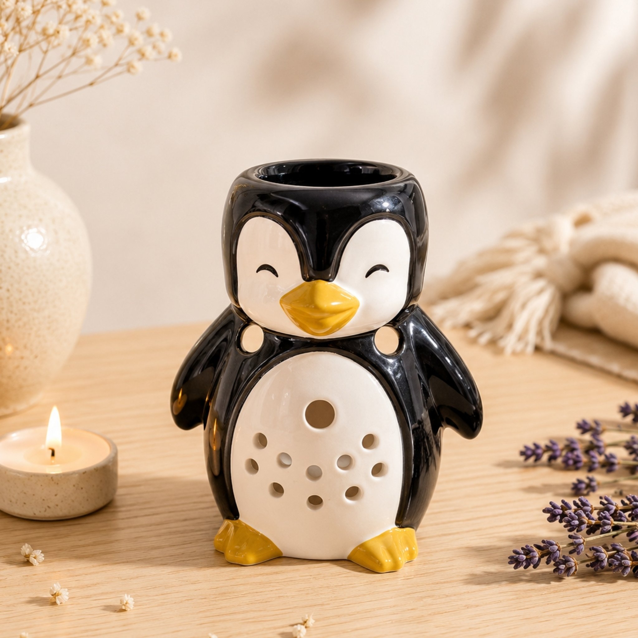Pinguin-Duftlampe aus Keramik neben Teelicht und Lavendel auf Holztisch