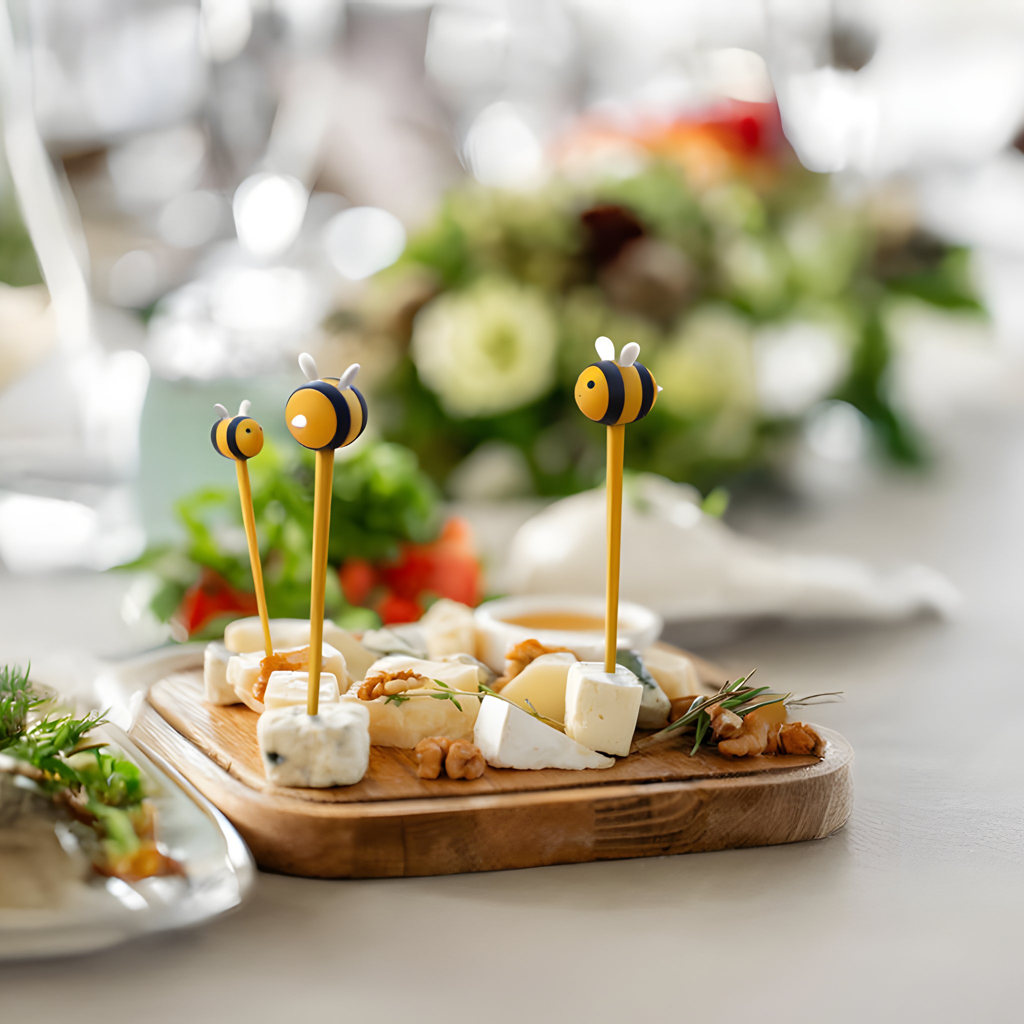 Käsewürfel auf einem Holzbrett beim Apéro, aufgespiesst mit den Bienen Foodpicks
