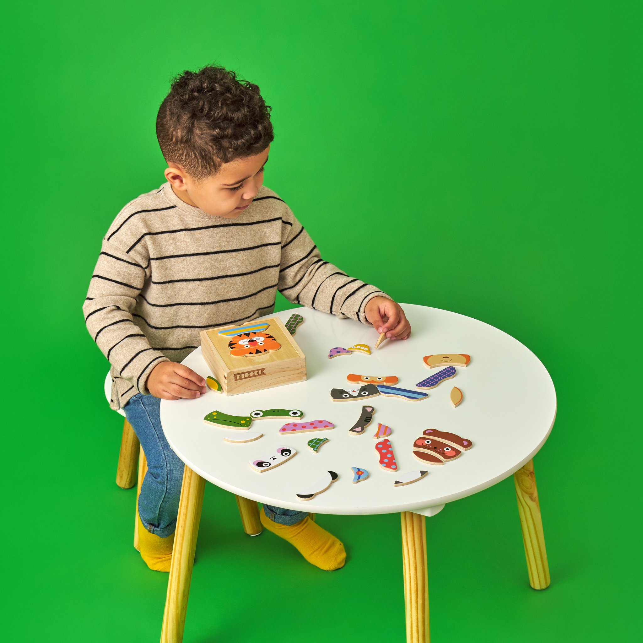 Boy at the table assembling pieces of the mix-up animal wooden puzzle