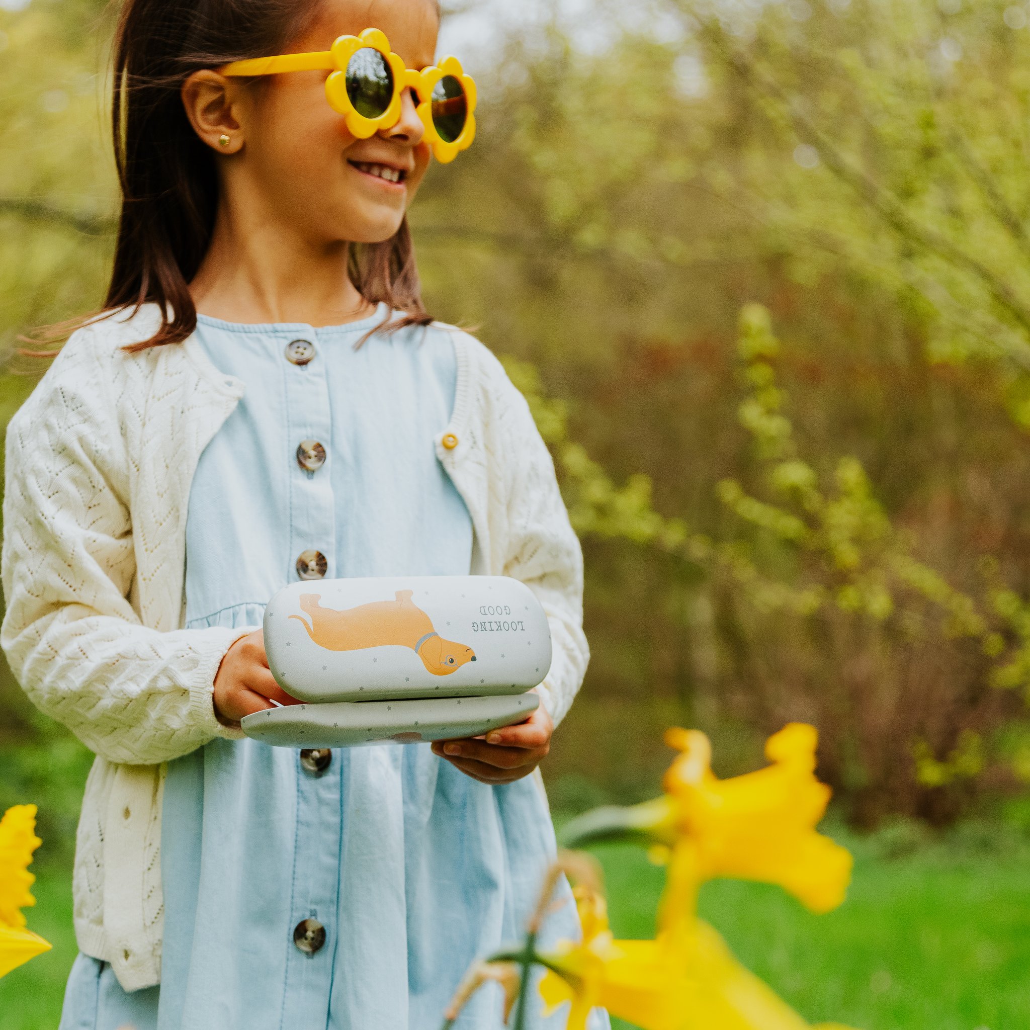 Girl with sunglasses holding the dachshund glasses case in the garden